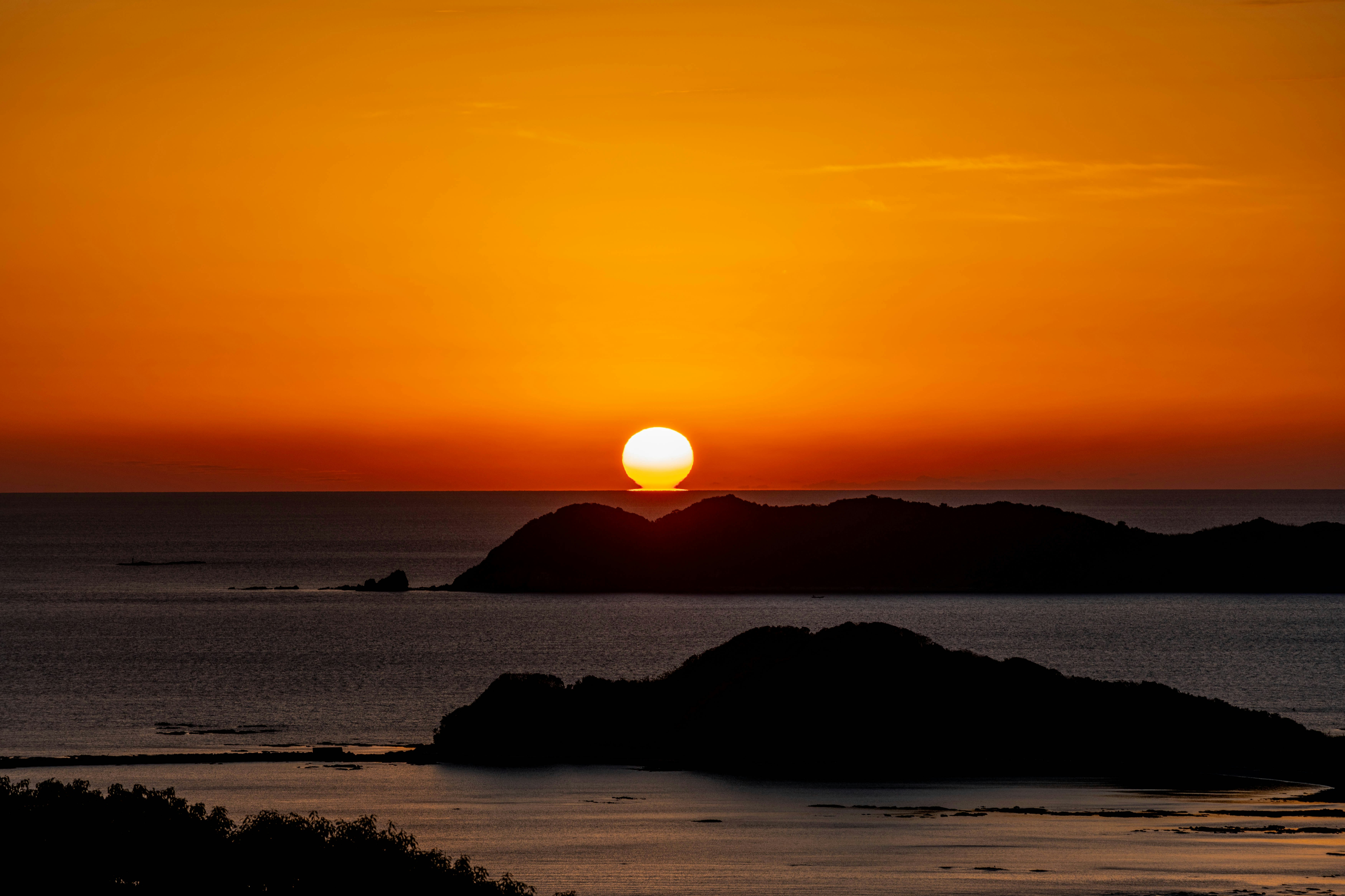 夕日に照らされた海と岬のシルエット