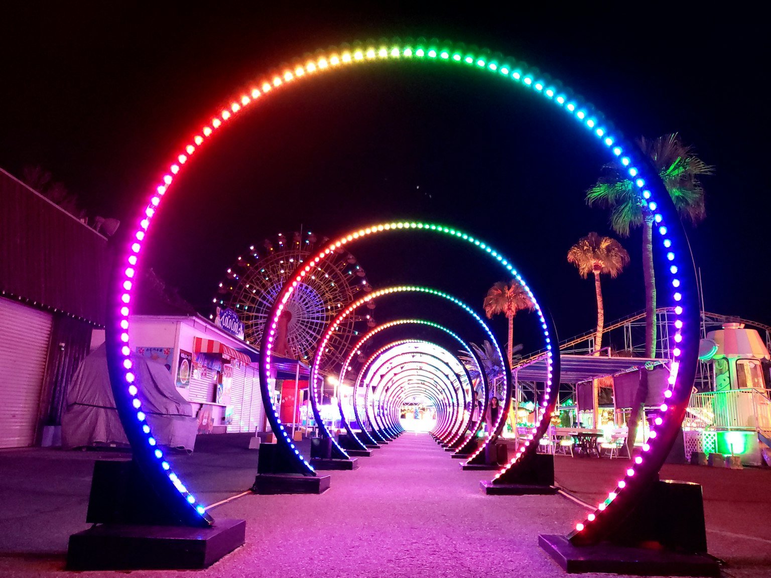 Tunnel ad arco LED colorato di notte con palme