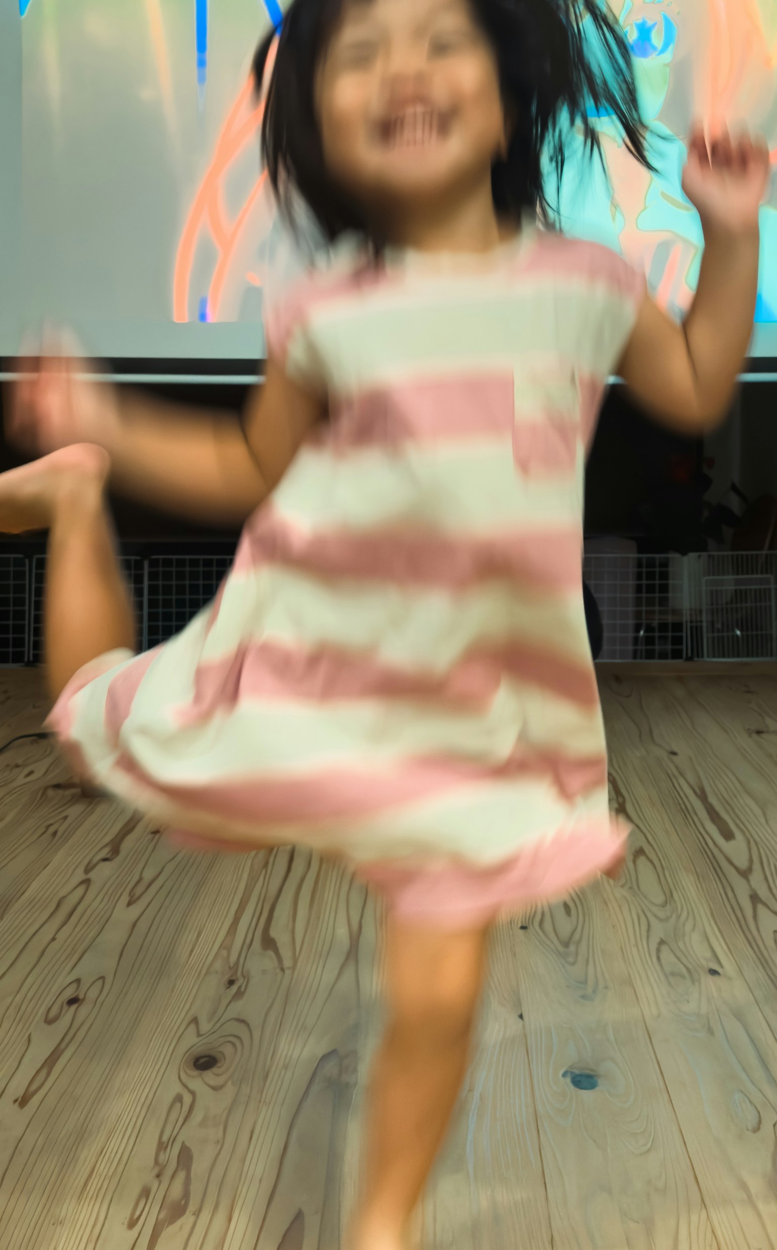 Niña pequeña en un vestido a rayas bailando alegremente con desenfoque de movimiento