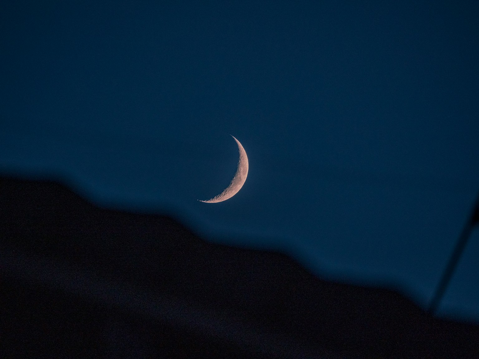 Sottile luna crescente nel cielo notturno con sfondo blu scuro