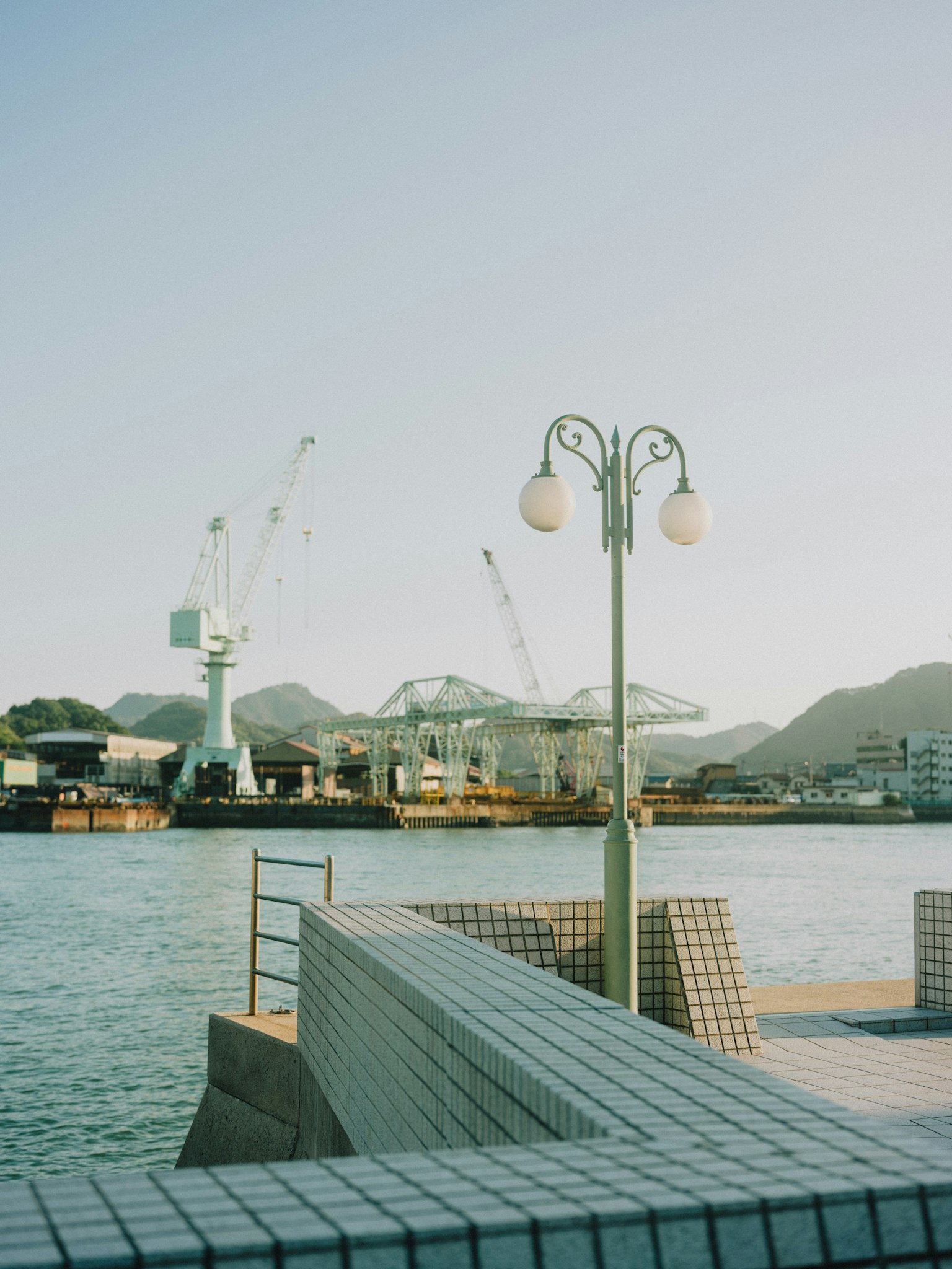 ทิวทัศน์ท่าเรือที่เงียบสงบมีเสาไฟและเครน