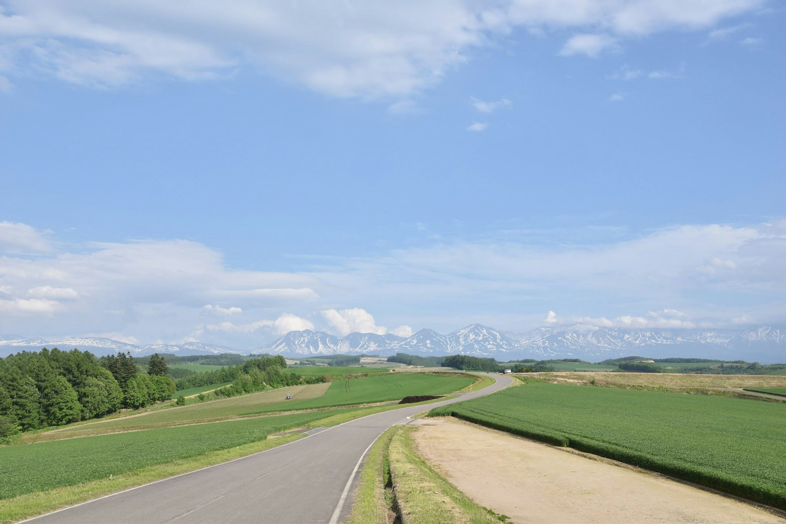 彎曲的道路與綠色田野和藍天背景