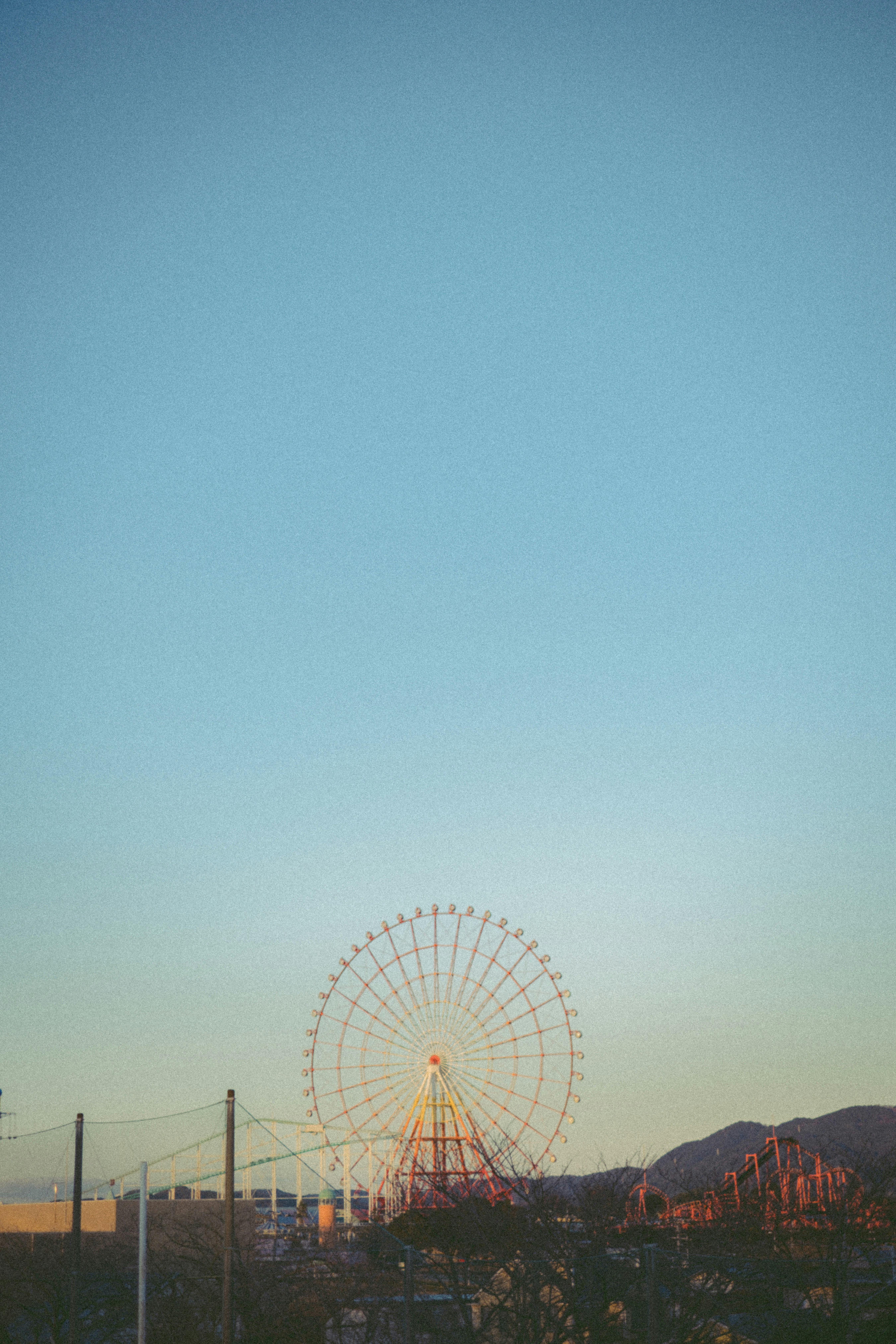 夕暮れの大観覧車と山並みの風景