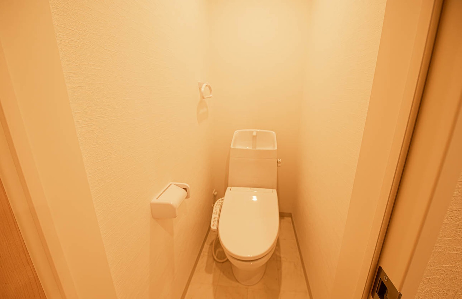 Innenansicht eines kleinen Badezimmers mit cremefarbenen Wänden und zentral positionierter Toilette