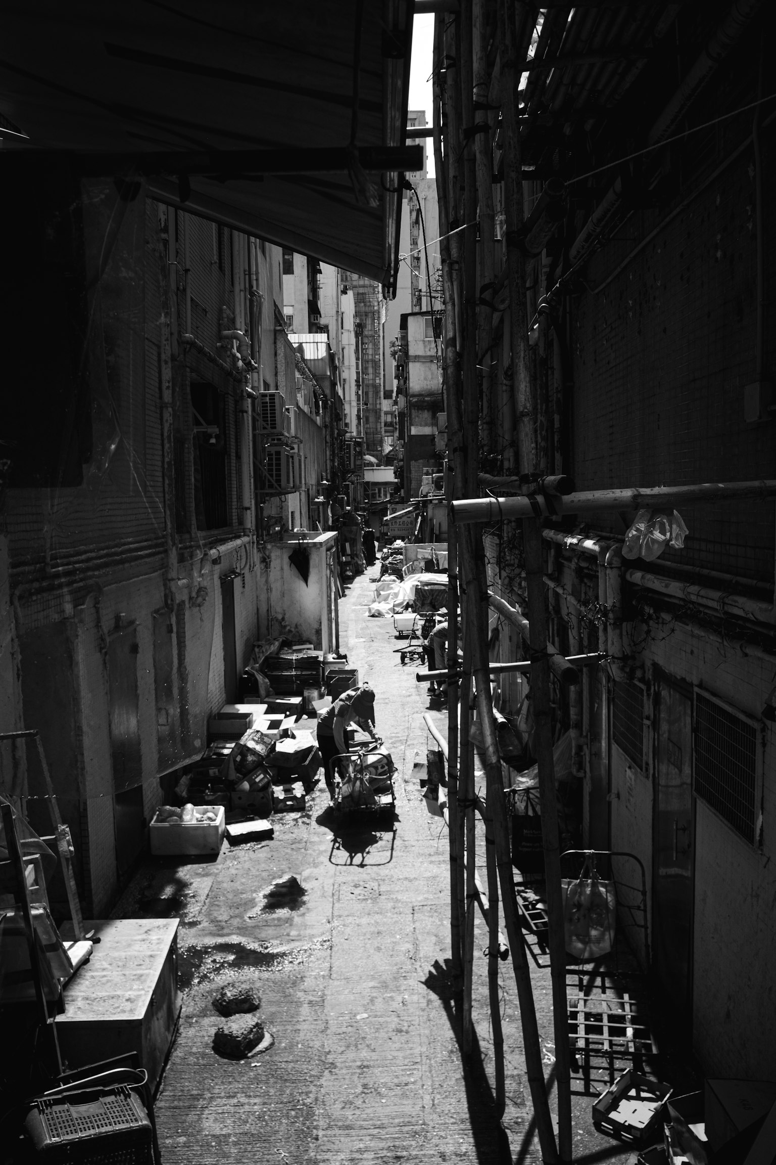 Narrow alley with scattered trash and scaffolding in black and white