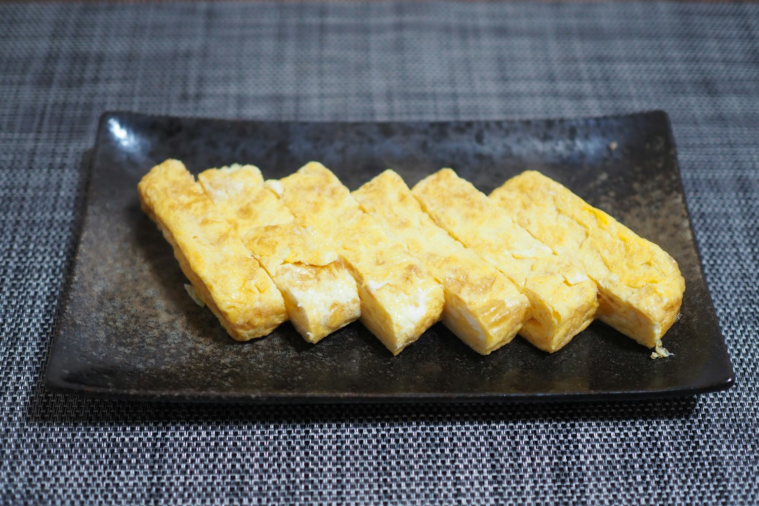 Lecker angeordnetes japanisches Omelett auf einem schwarzen Teller