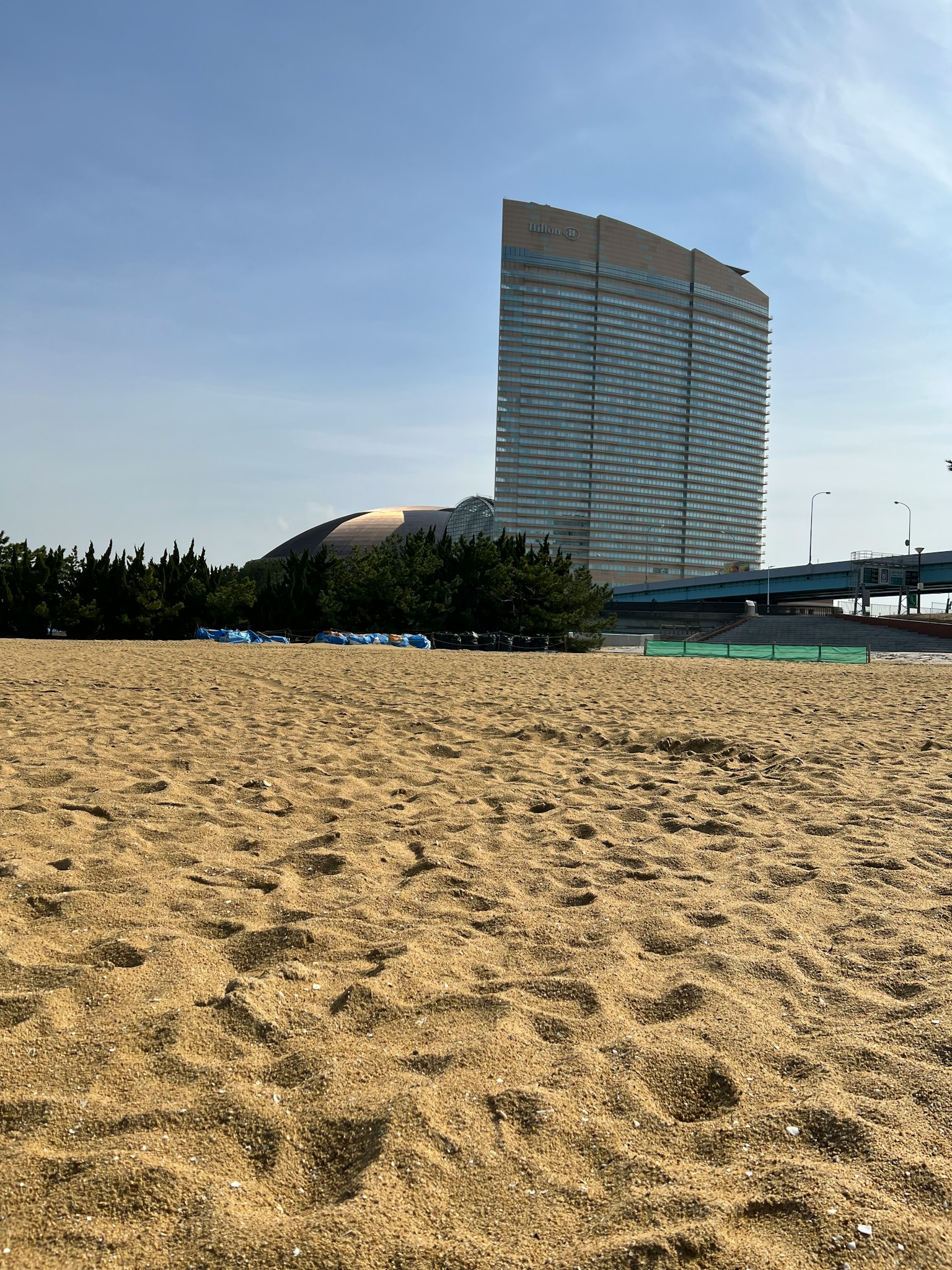 Vista di un grattacielo dalla spiaggia sabbiosa sotto un cielo azzurro