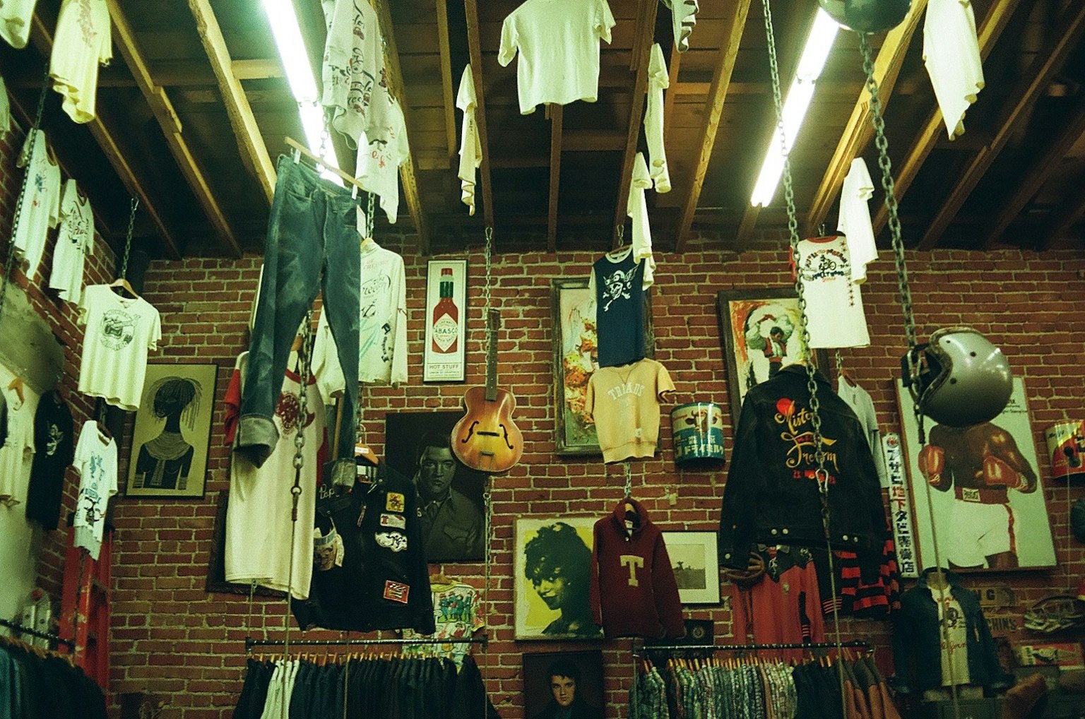 ภายในร้านเสื้อผ้าที่มีเสื้อผ้าลำลองแขวนและงานศิลปะ