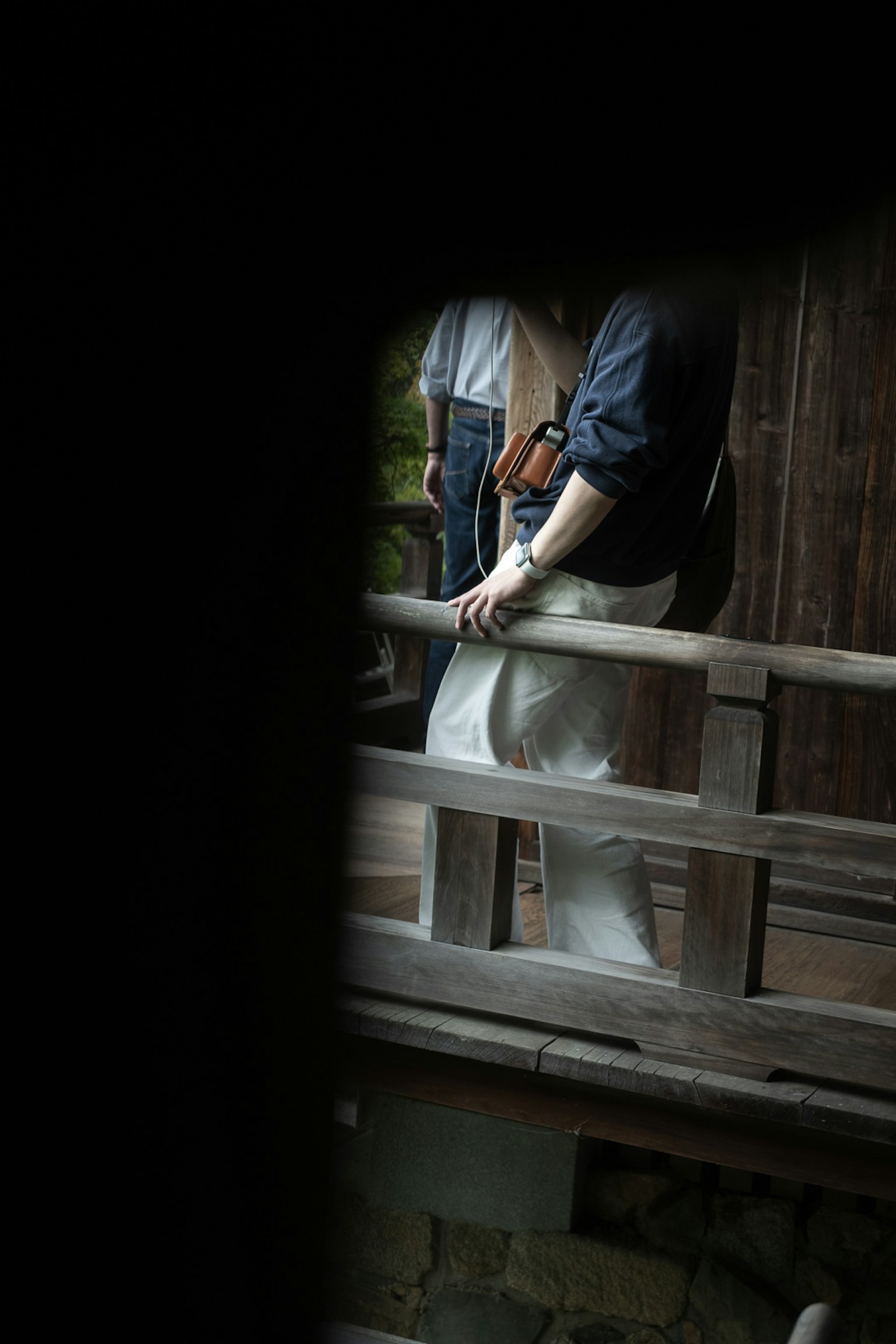 穿白色服装的人靠在木栏杆上，身旁有穿蓝色衣服的人