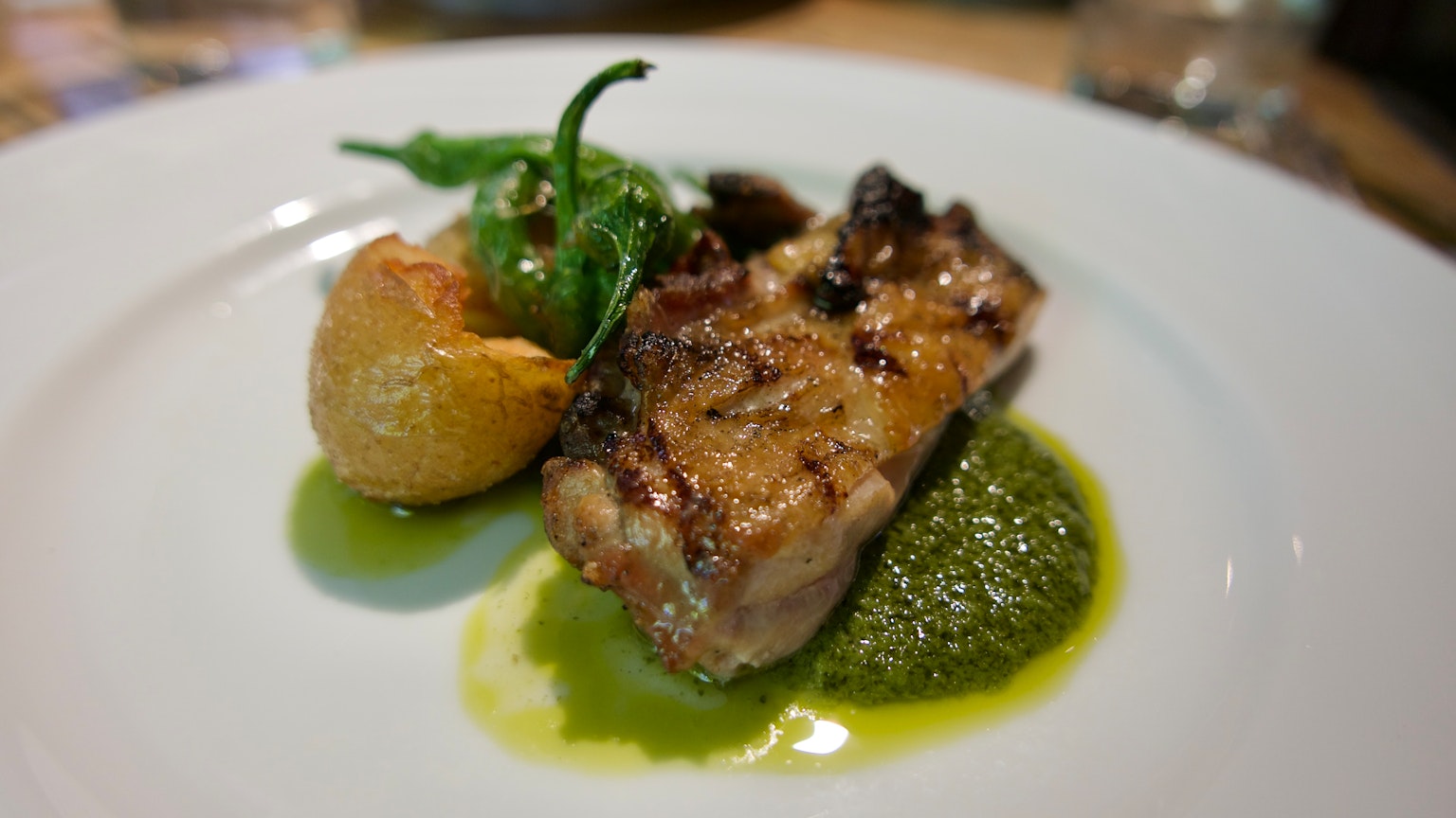 Piatto di carne grigliata con patate e salsa verde guarnito con peperone