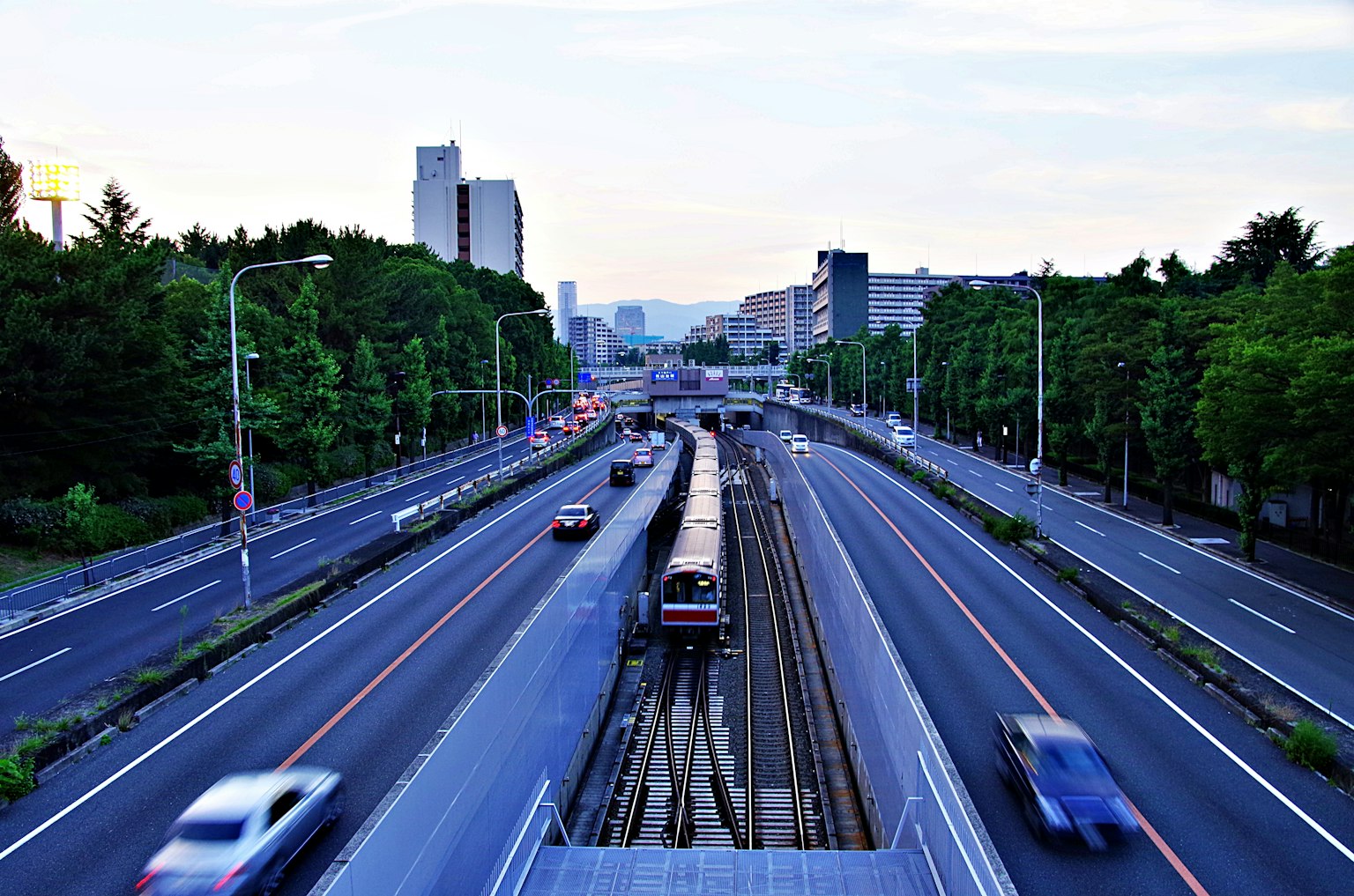 Stadtlandschaft mit erhobener Straße und Bahngleisen in der Dämmerung
