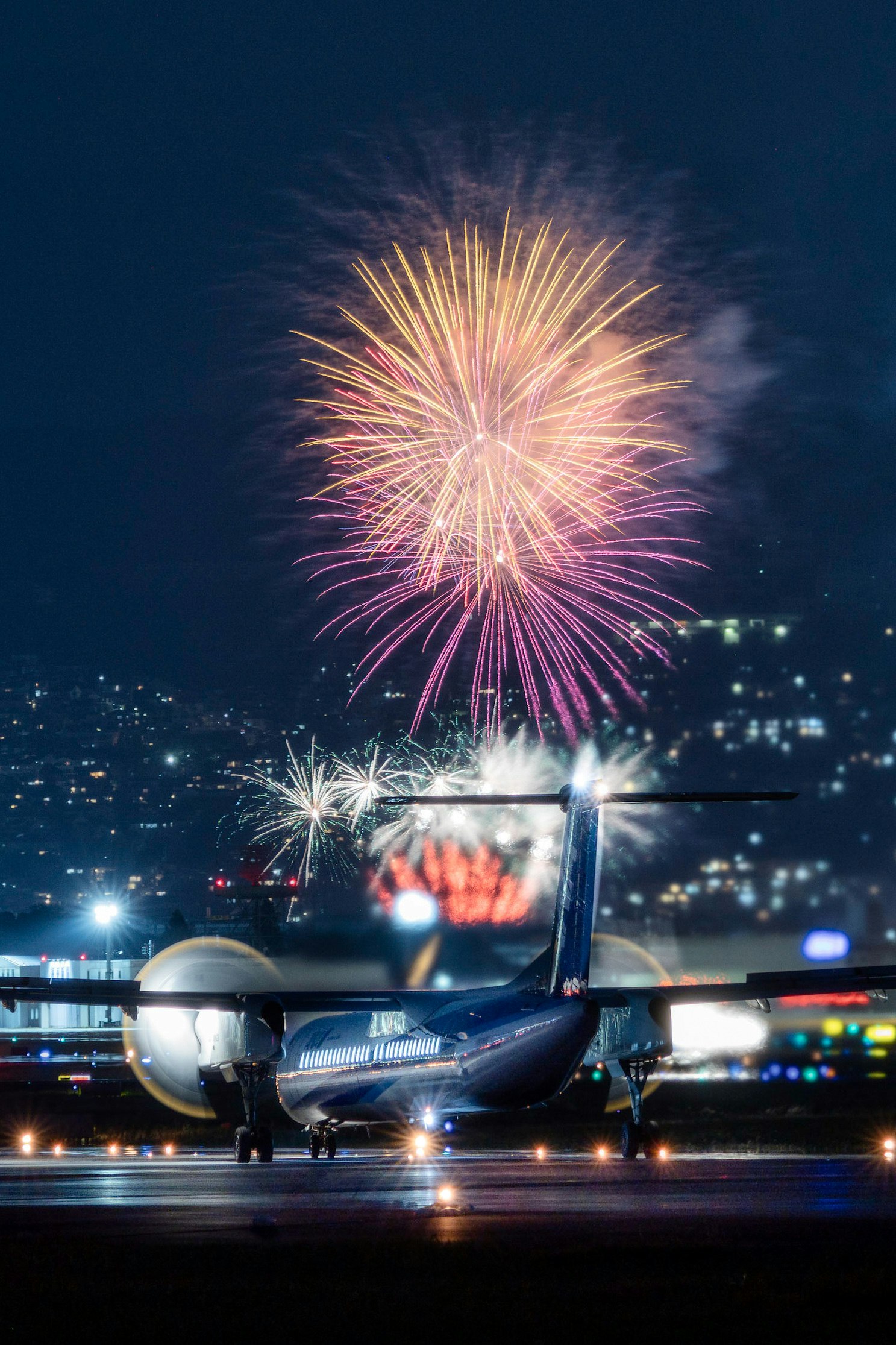 夜の滑走路で打ち上がる花火と飛行機