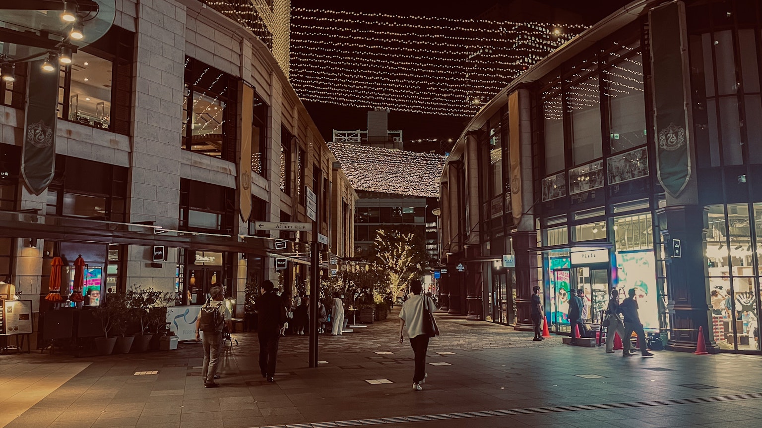Orang-orang berjalan di area perbelanjaan yang ramai di malam hari