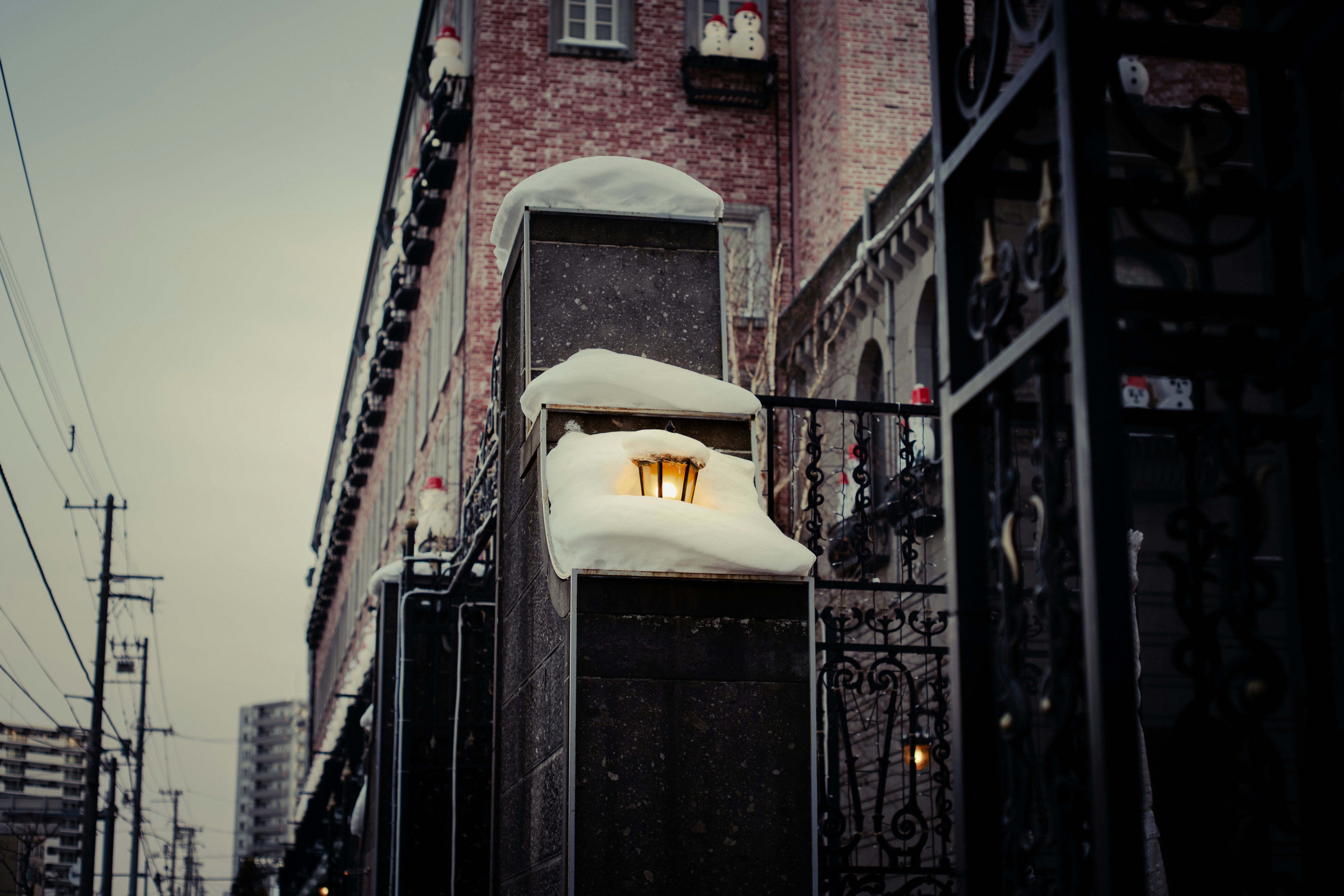 雪が積もった街灯とレンガの建物の一部が見える冬の風景