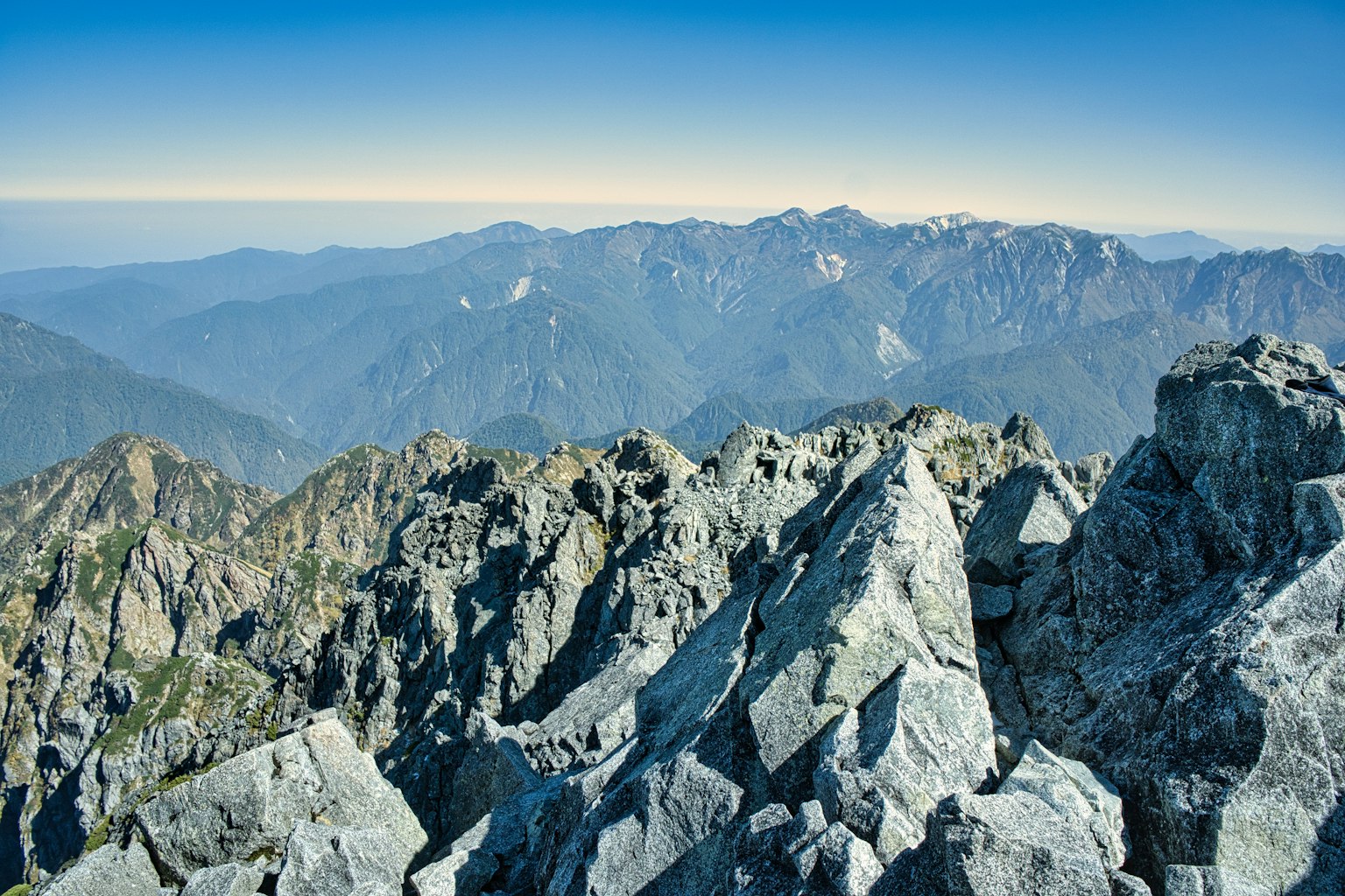 Vista dalla cima della montagna con rocce aguzze e montagne lontane