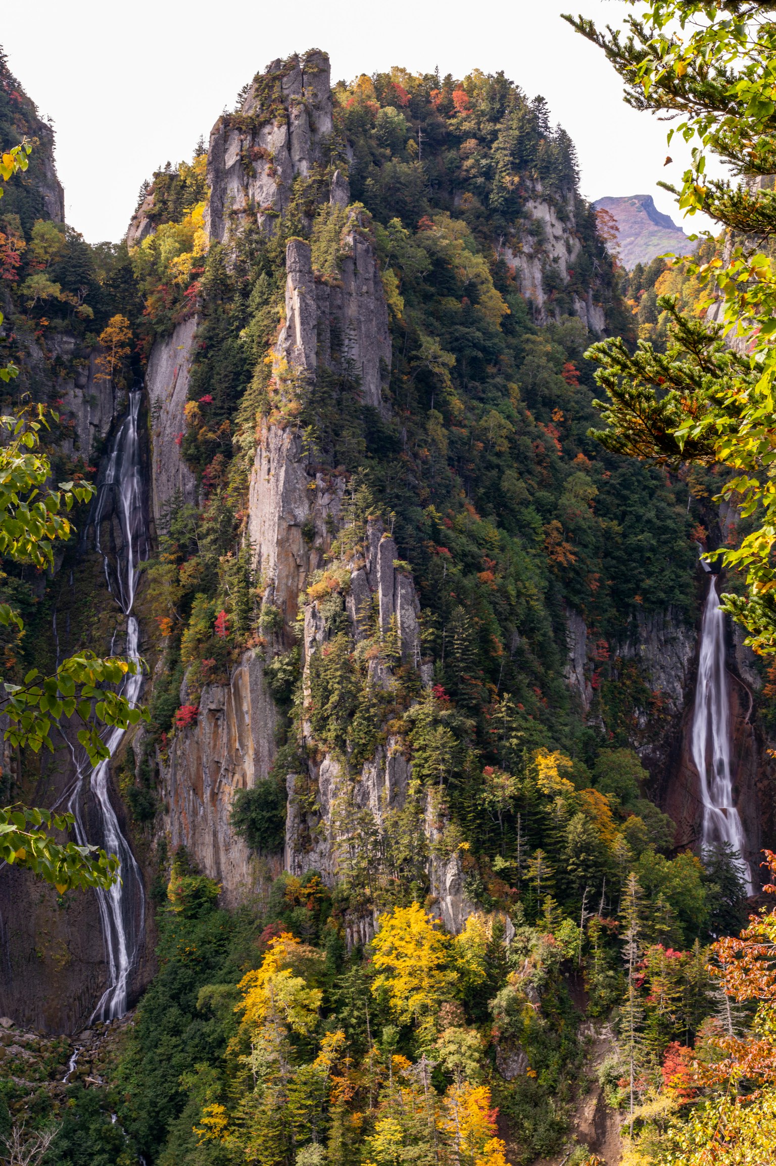 Vista escénica de una montaña con cascadas rodeada de colorido follaje de otoño
