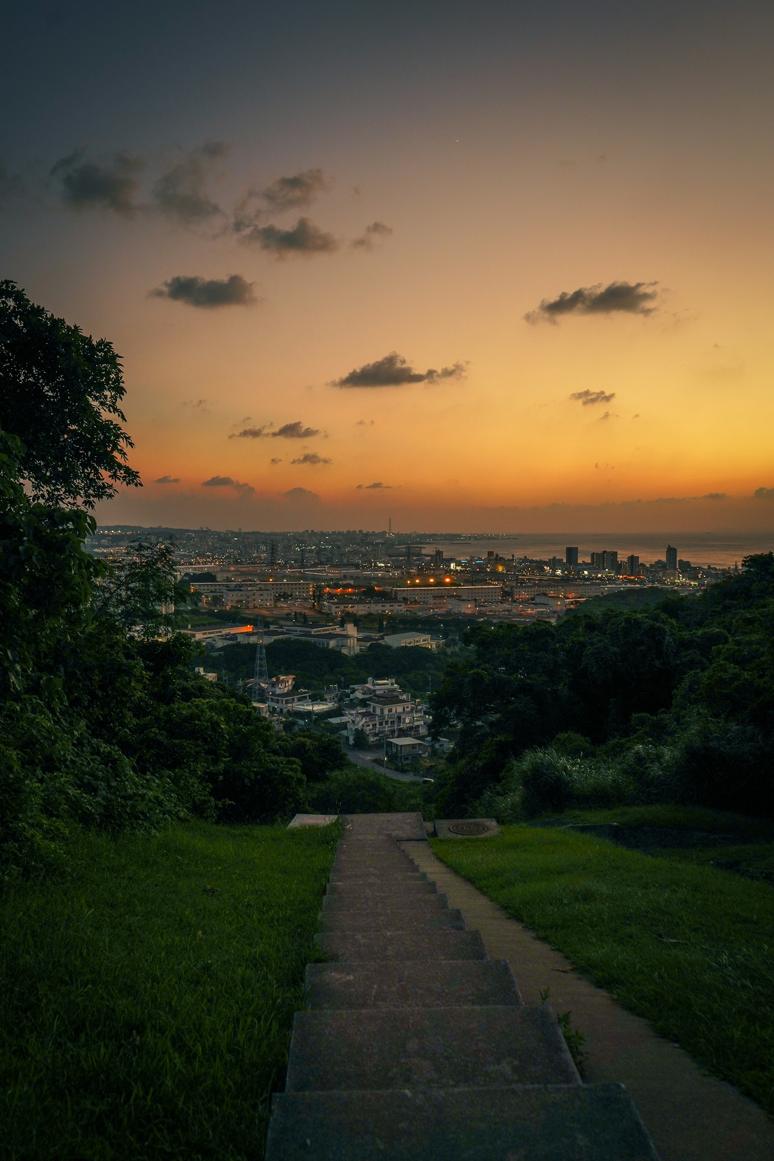 Staircase leading down to a city view at sunset with clouds