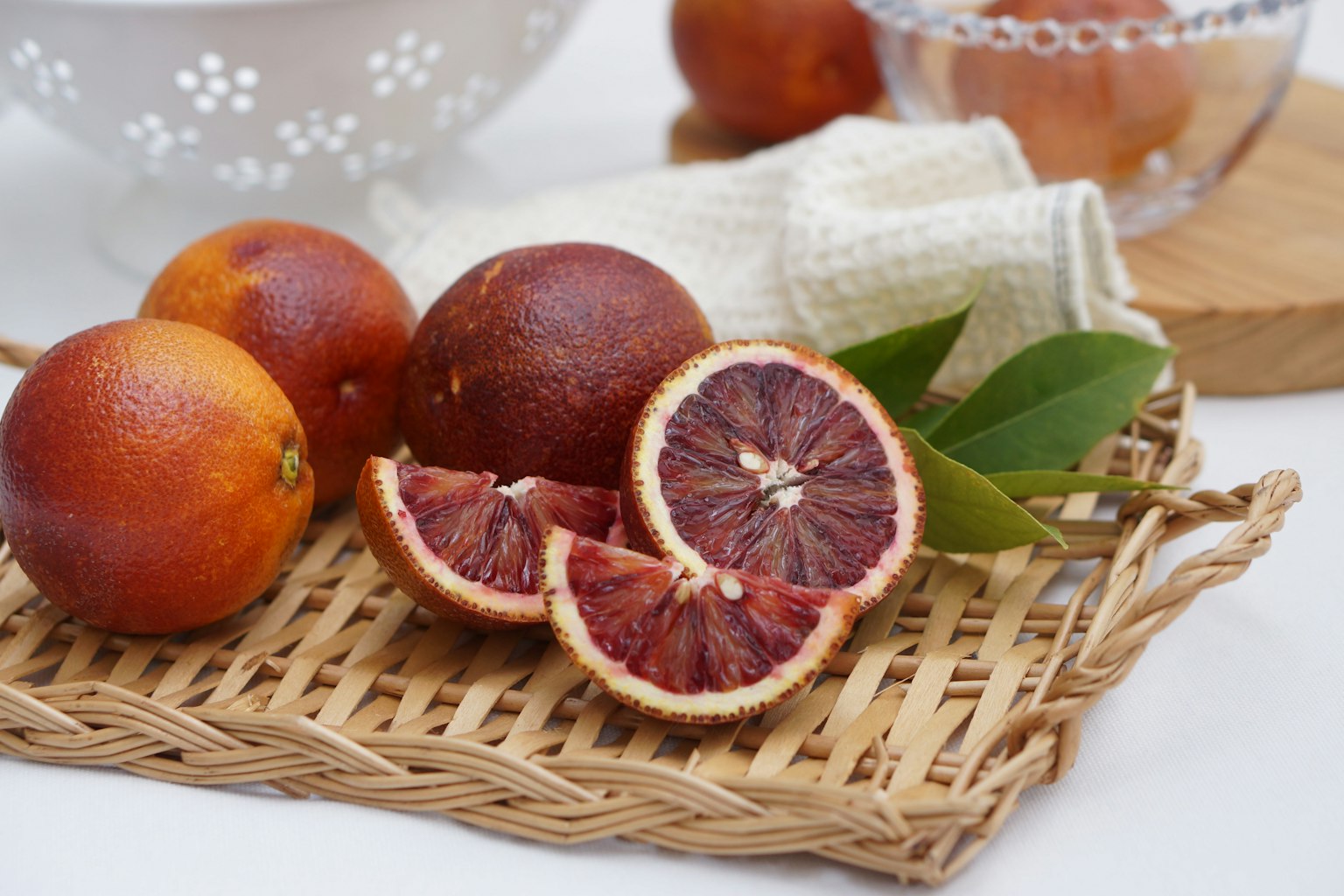 Blutorangen in einem Korb mit geschnittener Blutorange und grünen Blättern