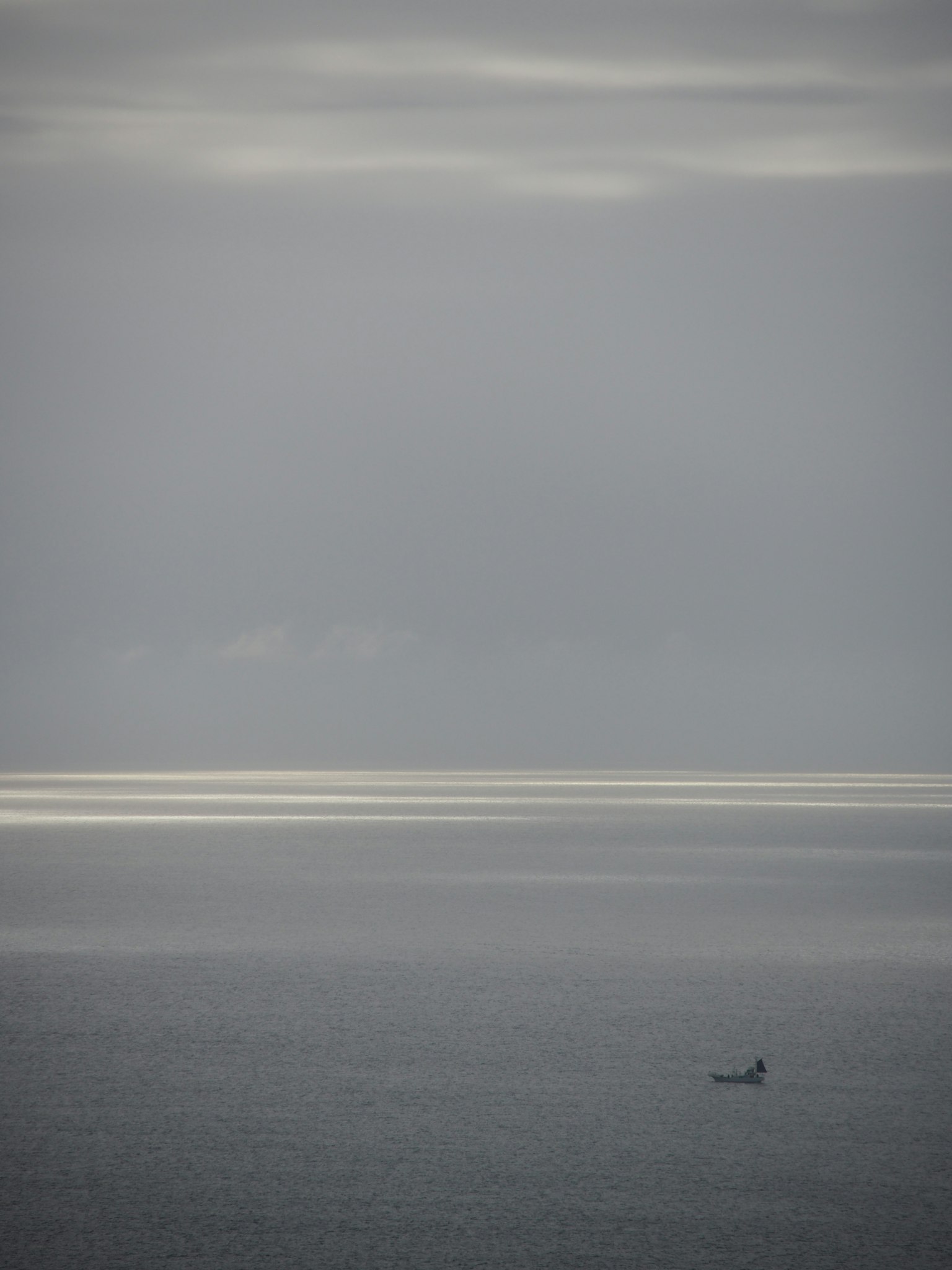 Una piccola barca che galleggia su un mare calmo sotto un cielo grigio