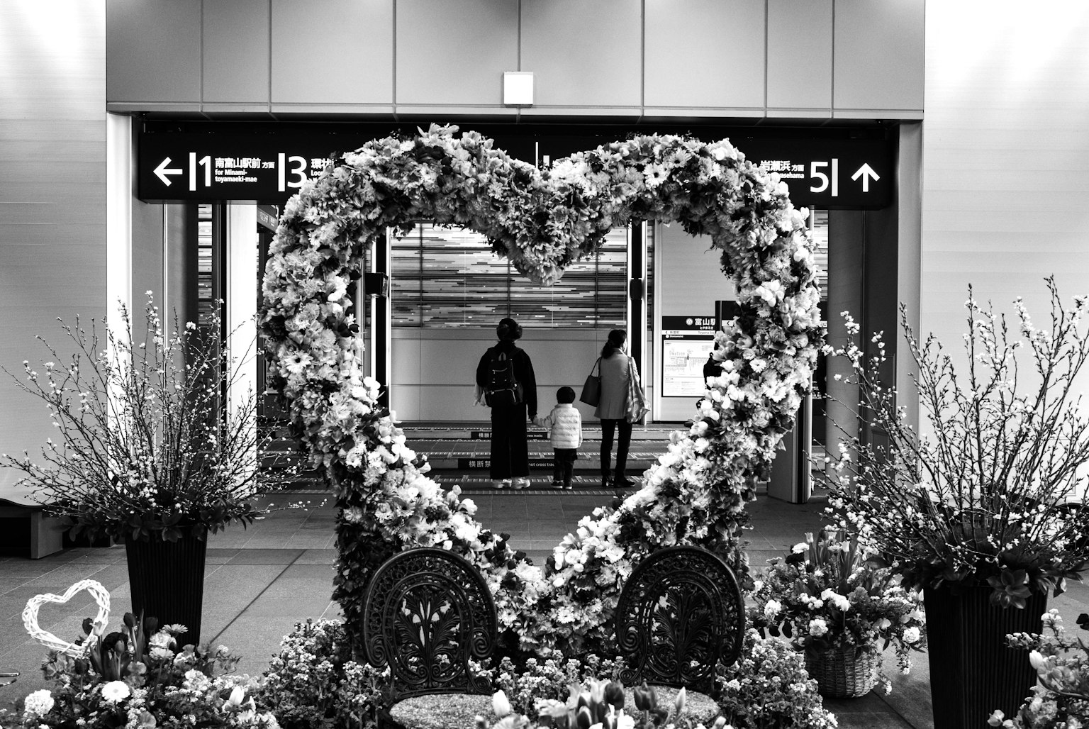 Arco a forma di cuore decorato con fiori con un genitore e un bambino sullo sfondo