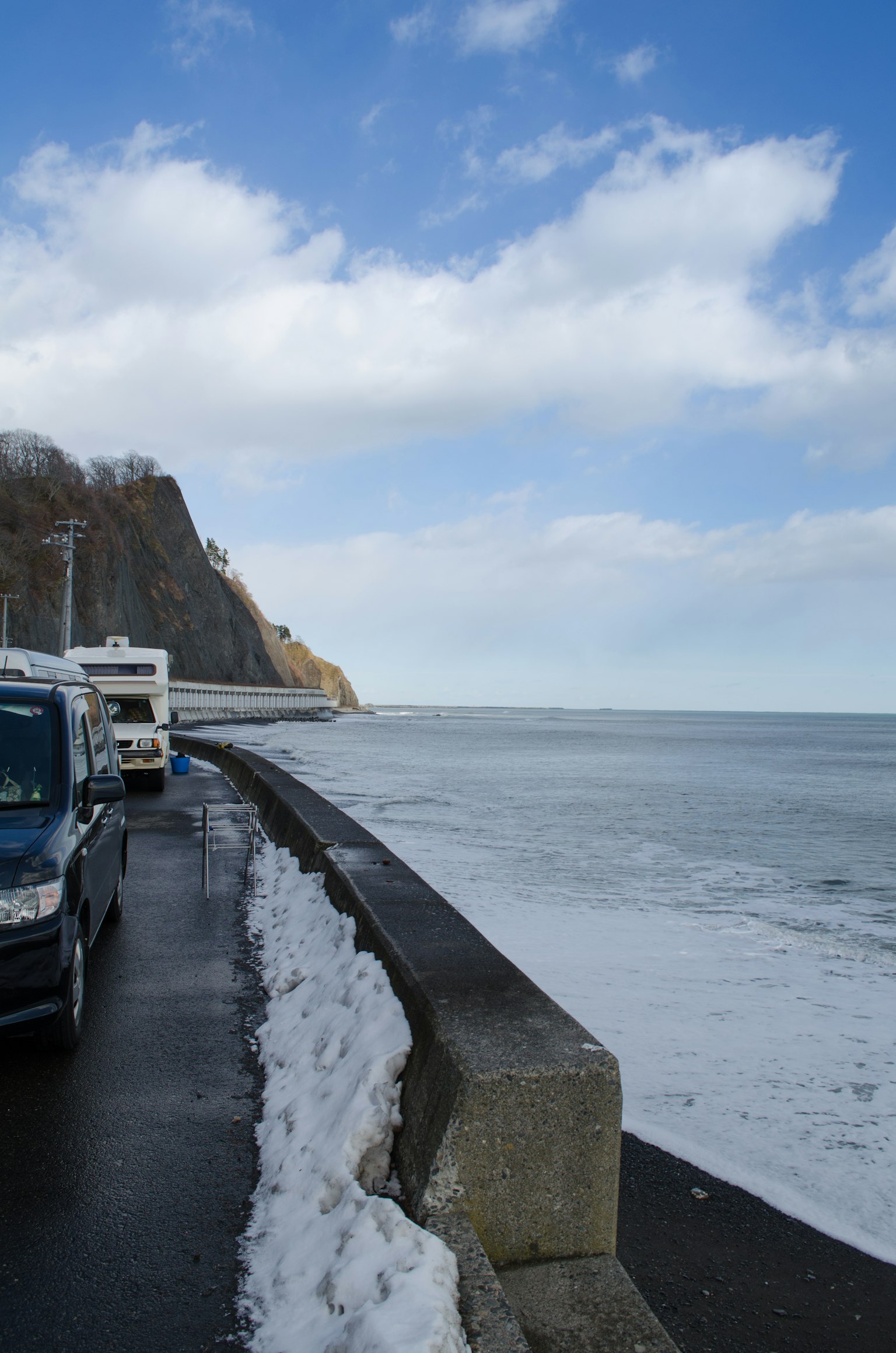 Route enneigée au bord de l'océan avec ciel bleu et nuages