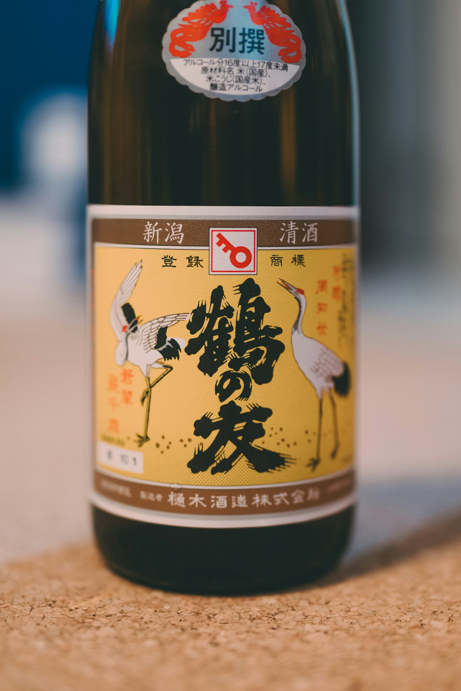 Bouteille de saké étiquetée en jaune avec des illustrations de grues
