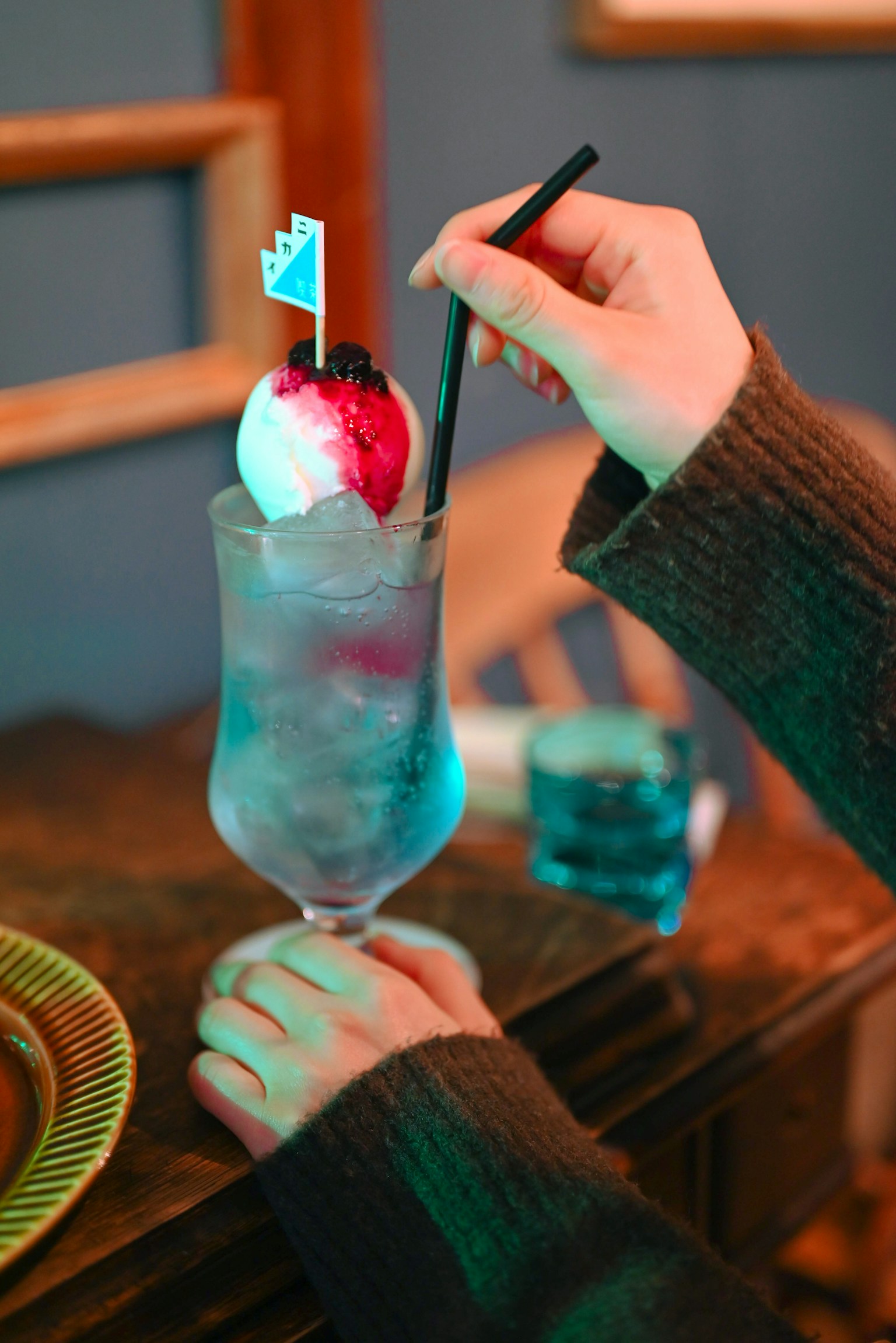 一只手握着一杯彩色鸡尾酒，上面有冰块和樱桃