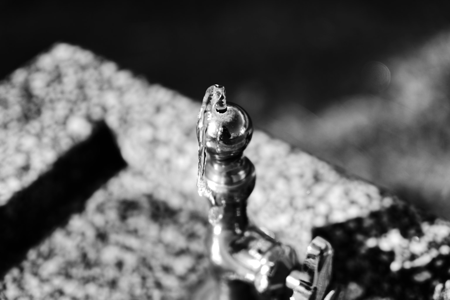 Close-up of a silver metal faucet in black and white with a distinctive spout