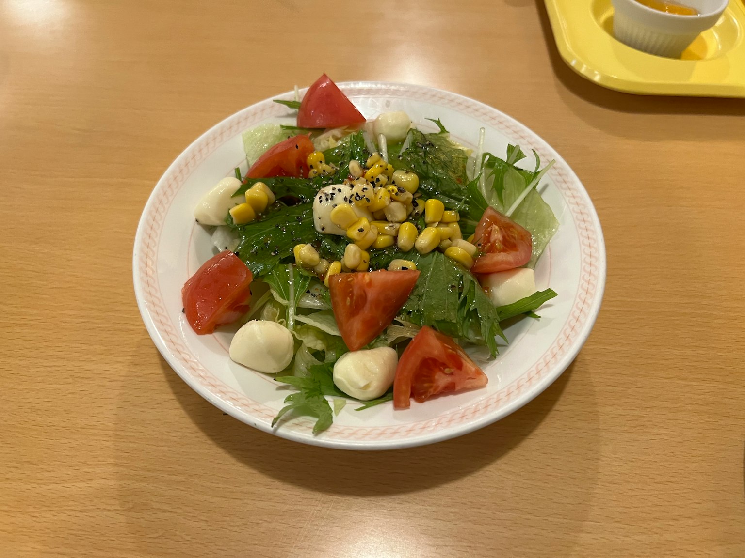 Tazón de ensalada fresca con tomates, maíz, mozzarella y hojas verdes