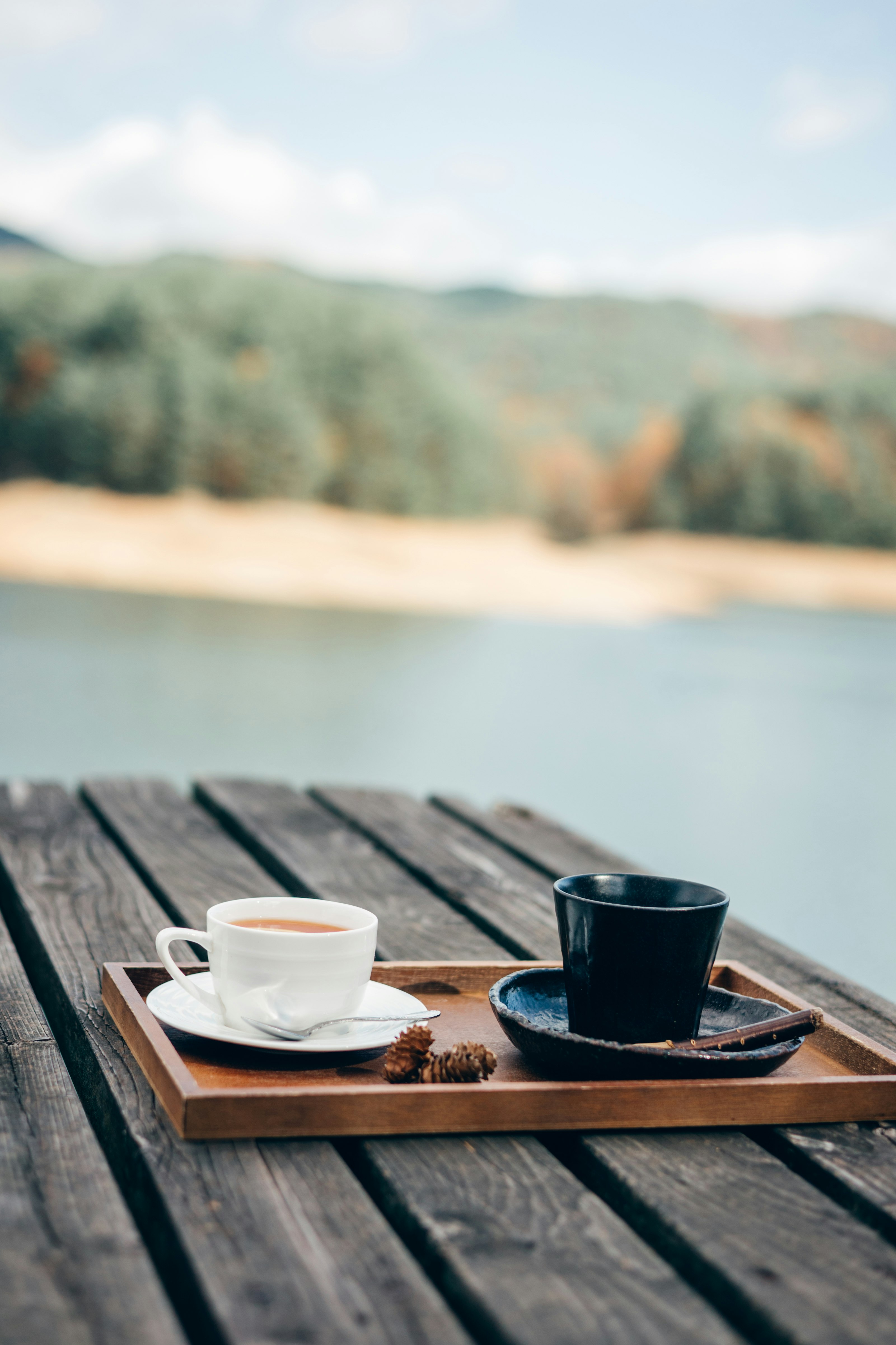 湖邊木桌上的咖啡與茶杯