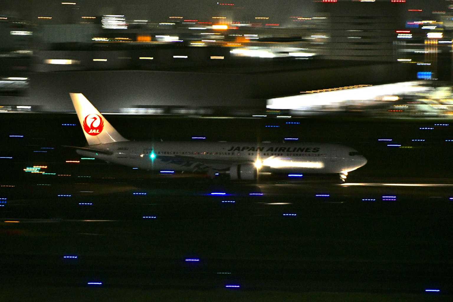 Avion de Japan Airlines atterrissant sur la piste de nuit