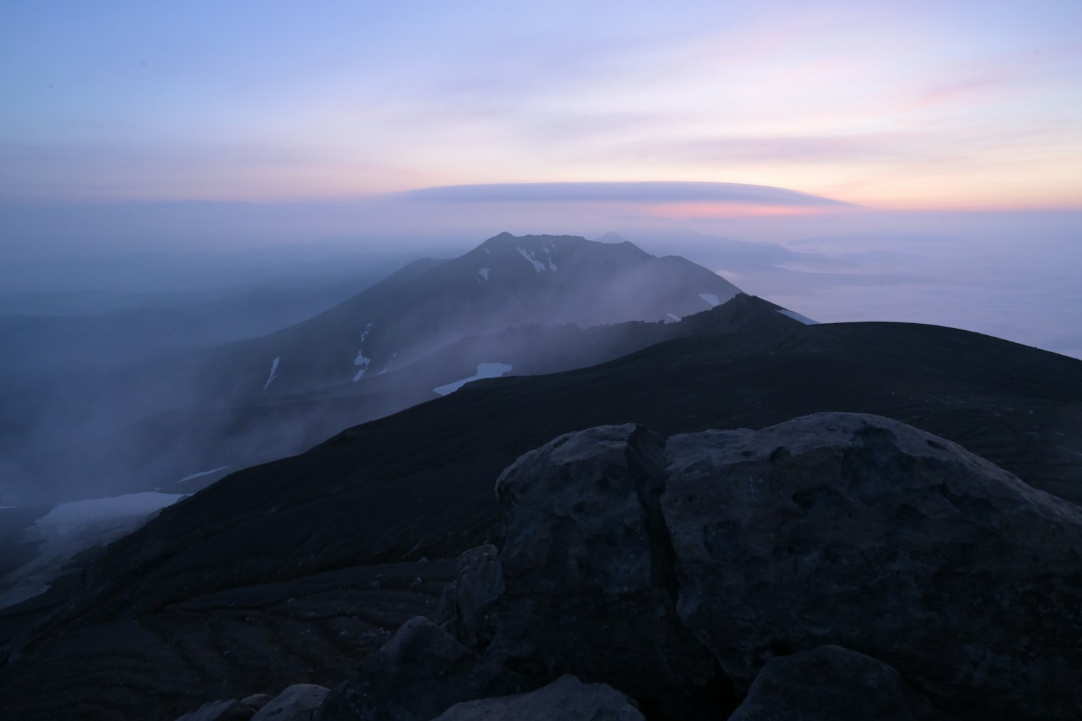 Pemandangan senja yang indah dengan punggungan gunung dan kabut