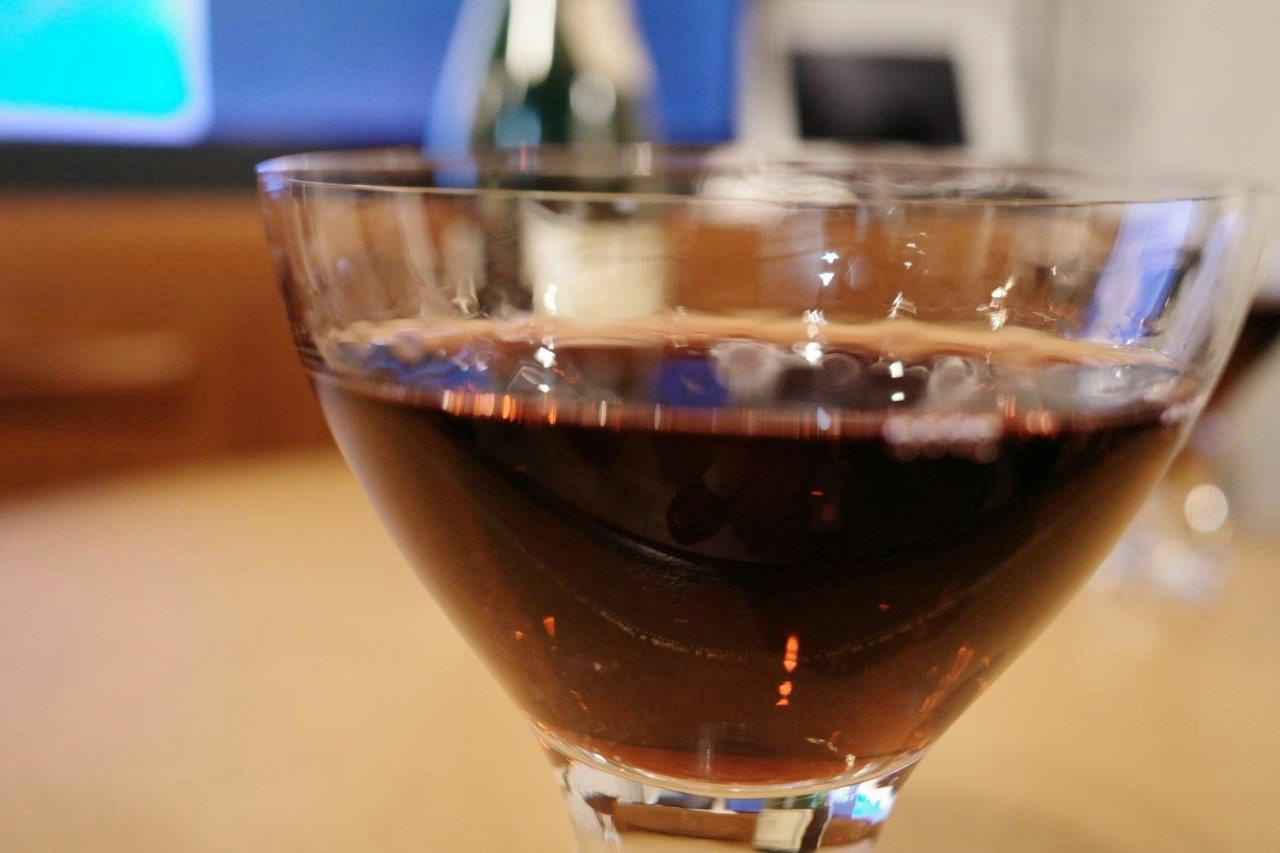 Close-up of a glass filled with red wine bubbles visible at the bottom