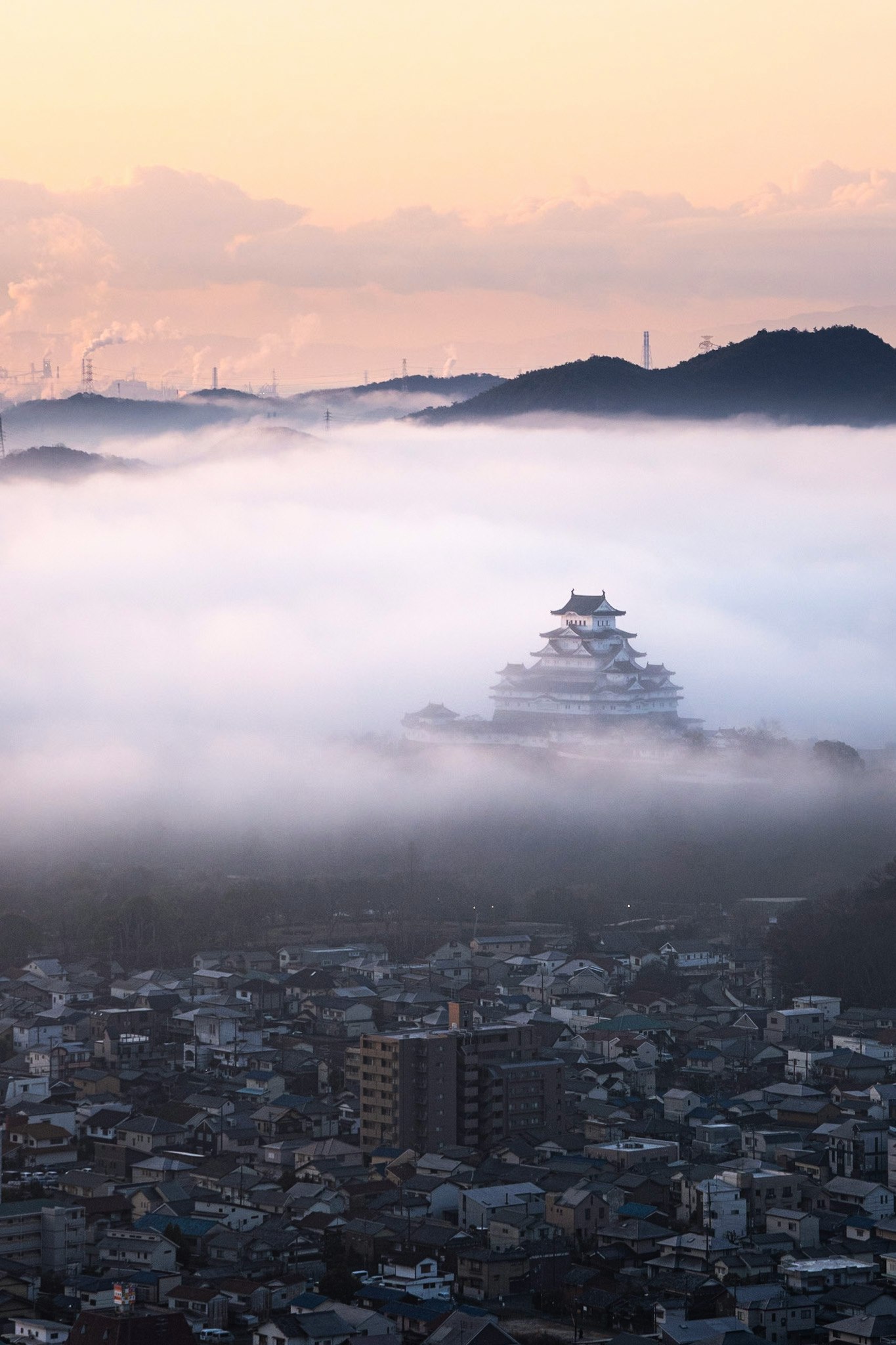 霧に包まれた街並みと遠景の城郭風の建物