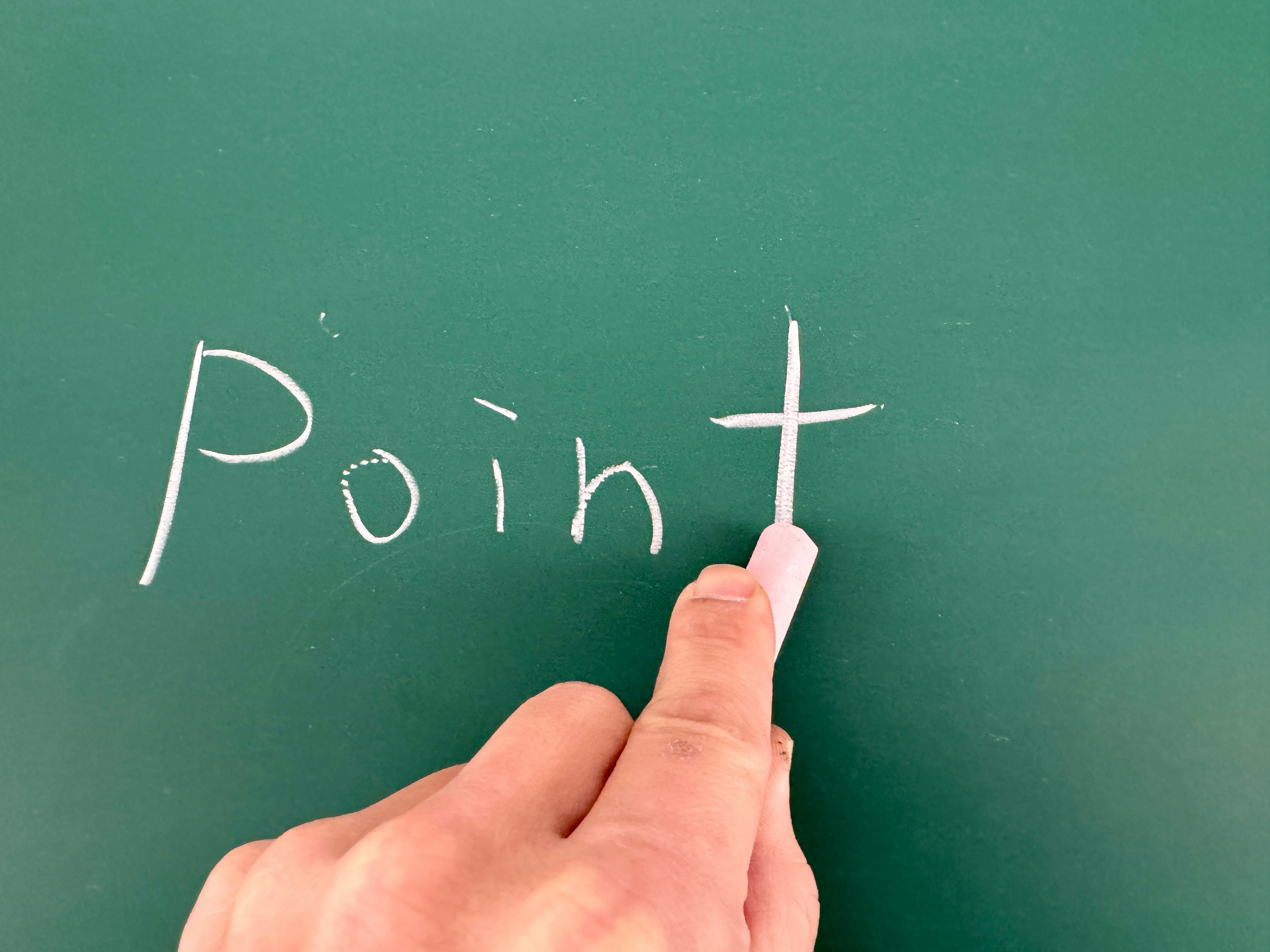 hand holding chalk writing “Point” on a chalkboard