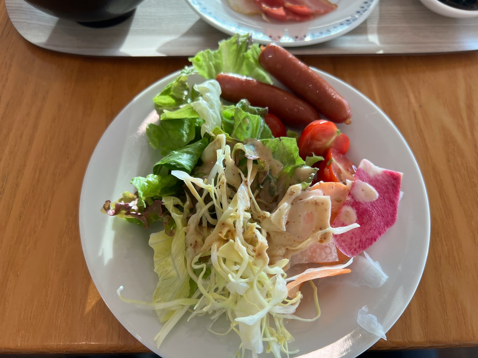 Un piatto con insalata, salsicce e pomodori