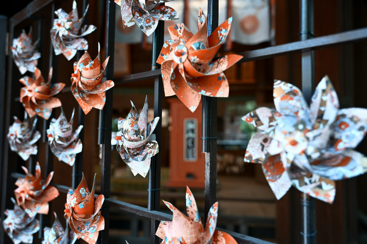 Fleurs en papier orange et blanc disposées sur une clôture en métal