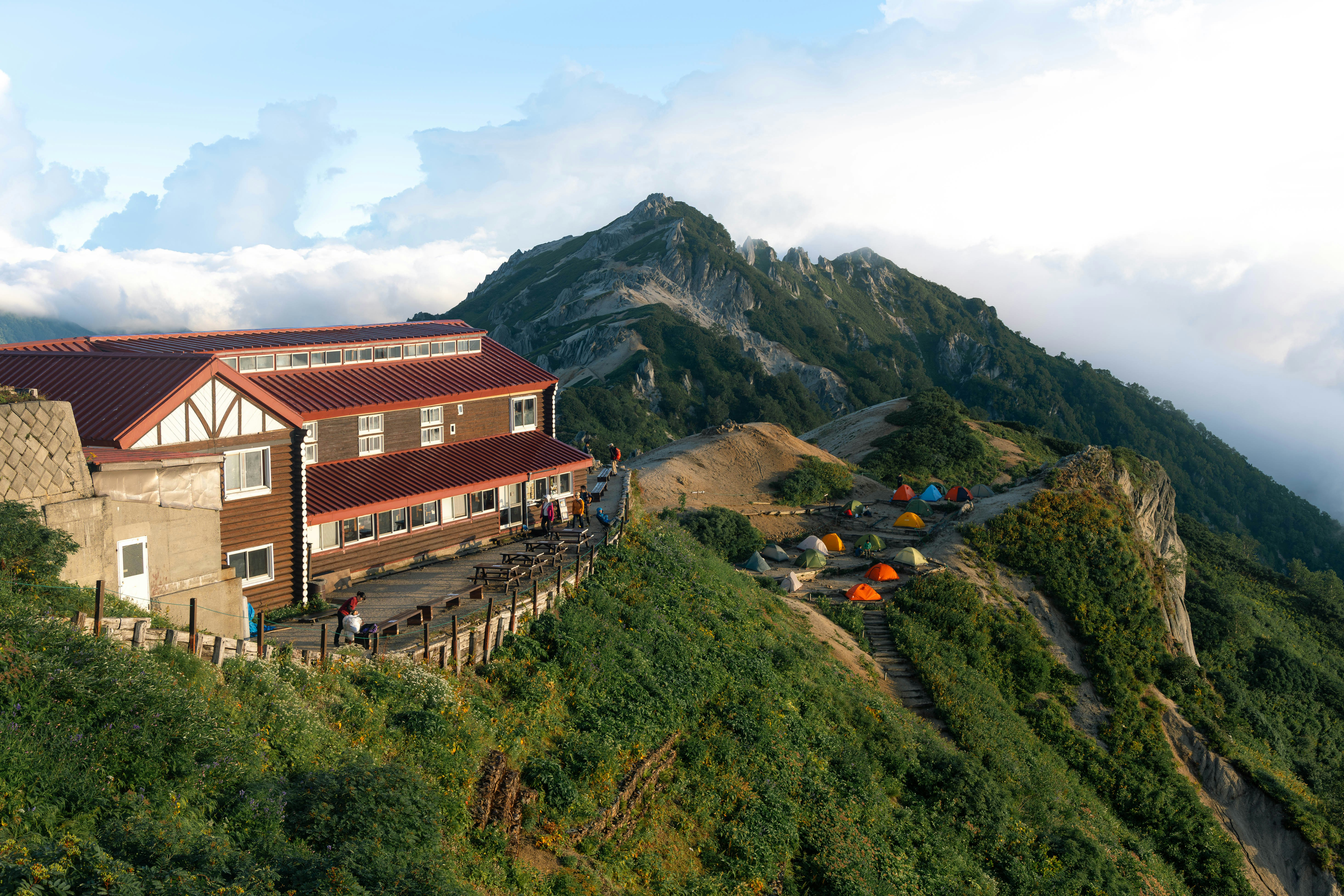 山腹に建つ山小屋と登山道のある景色