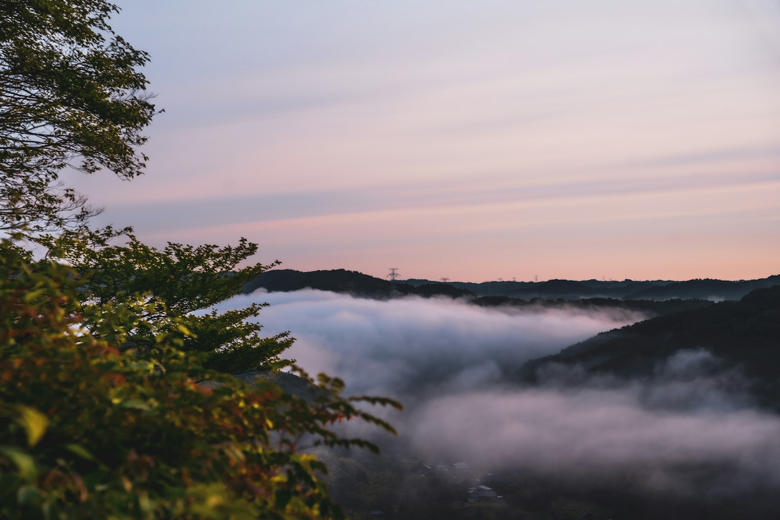 Montagnes enveloppées de brume avec un ciel de coucher de soleil doux