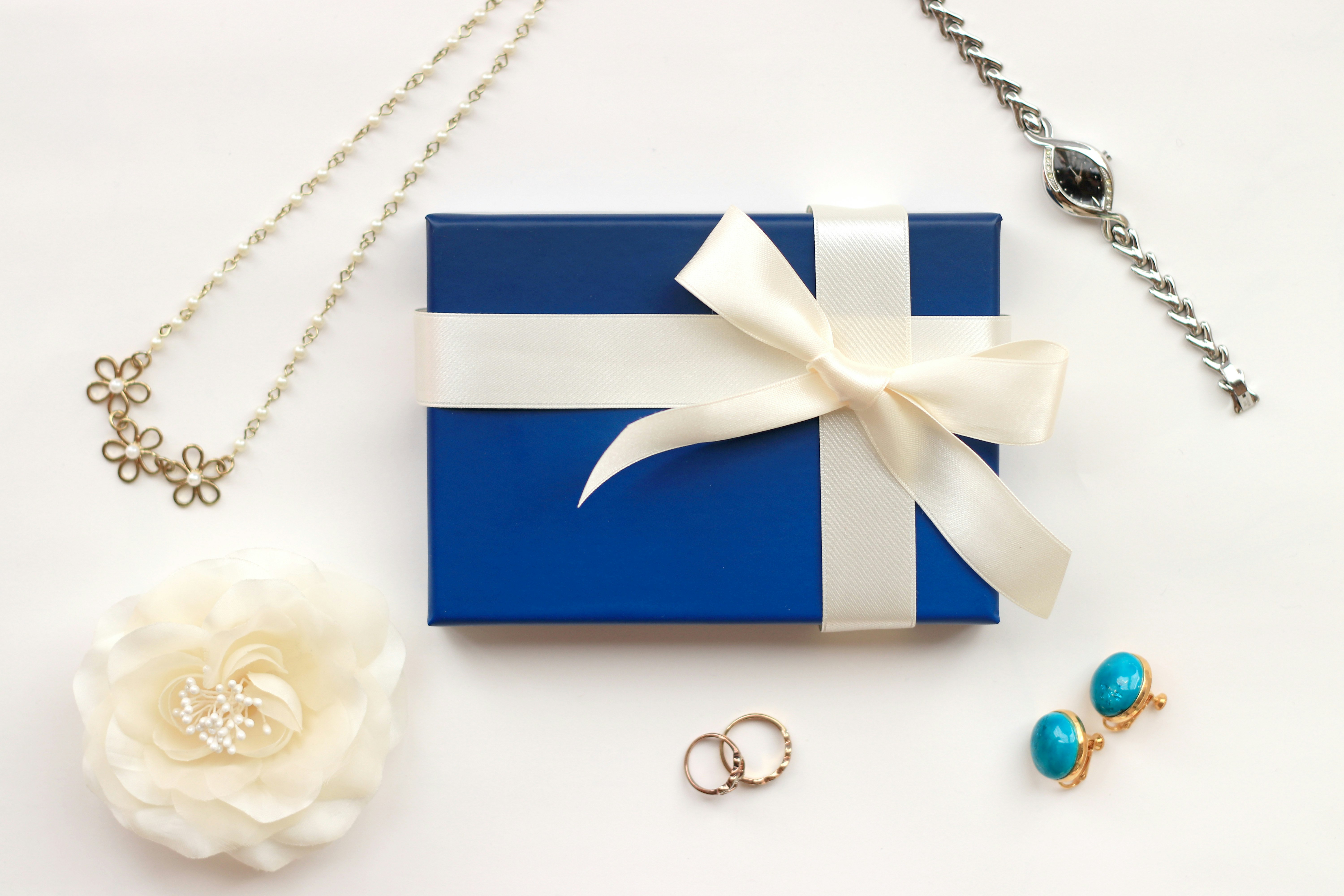 Scatola regalo blu con nastro e accessori di gioielli su sfondo bianco