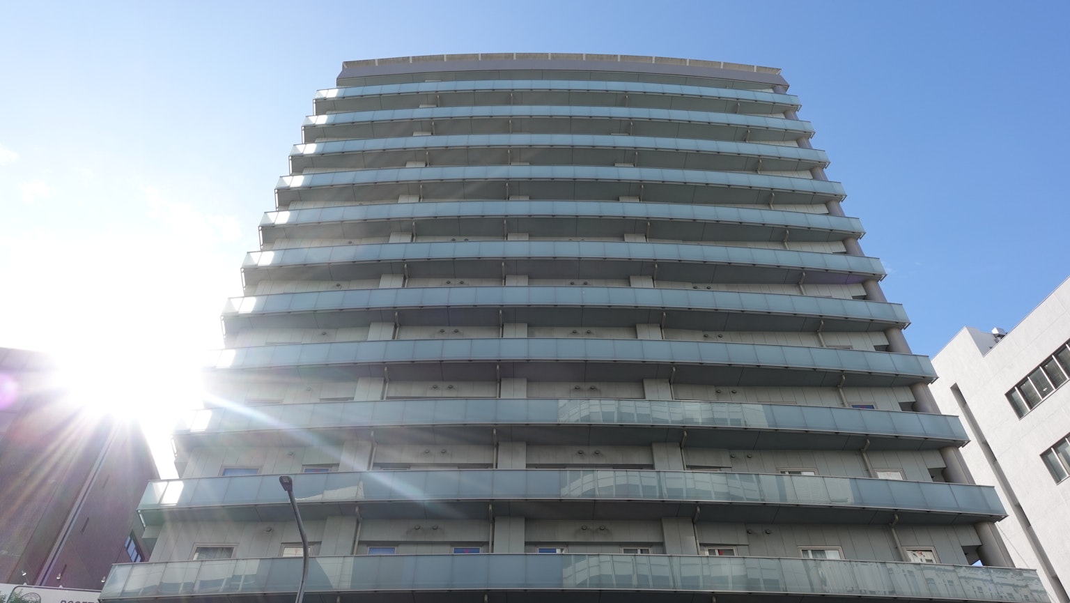 Edificio moderno a più piani con balconi in vetro sotto un cielo sereno e soleggiato