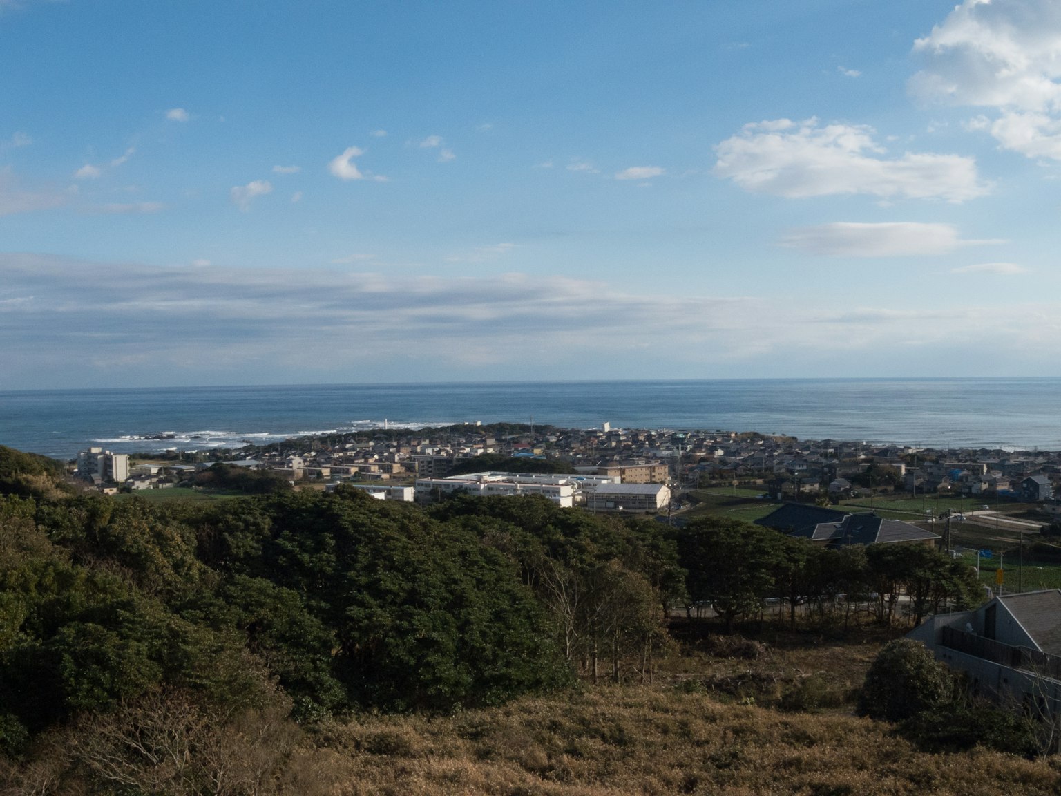 Panoramablick auf eine Stadt mit blauem Himmel und Meer grüne Hügel und sichtbare Gebäude