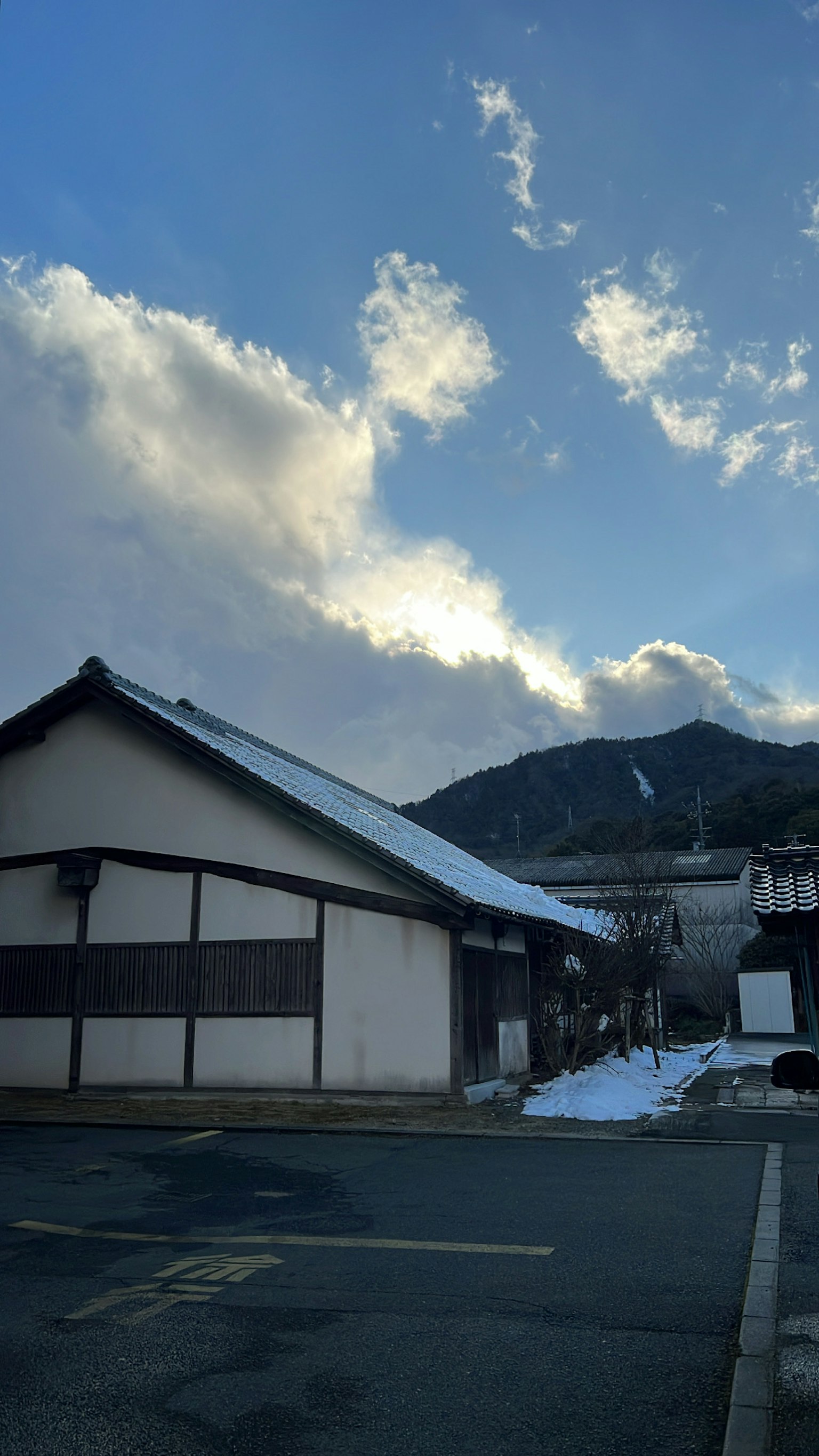 Traditionelles japanisches Gebäude mit Schnee und Bergen unter blauem Himmel
