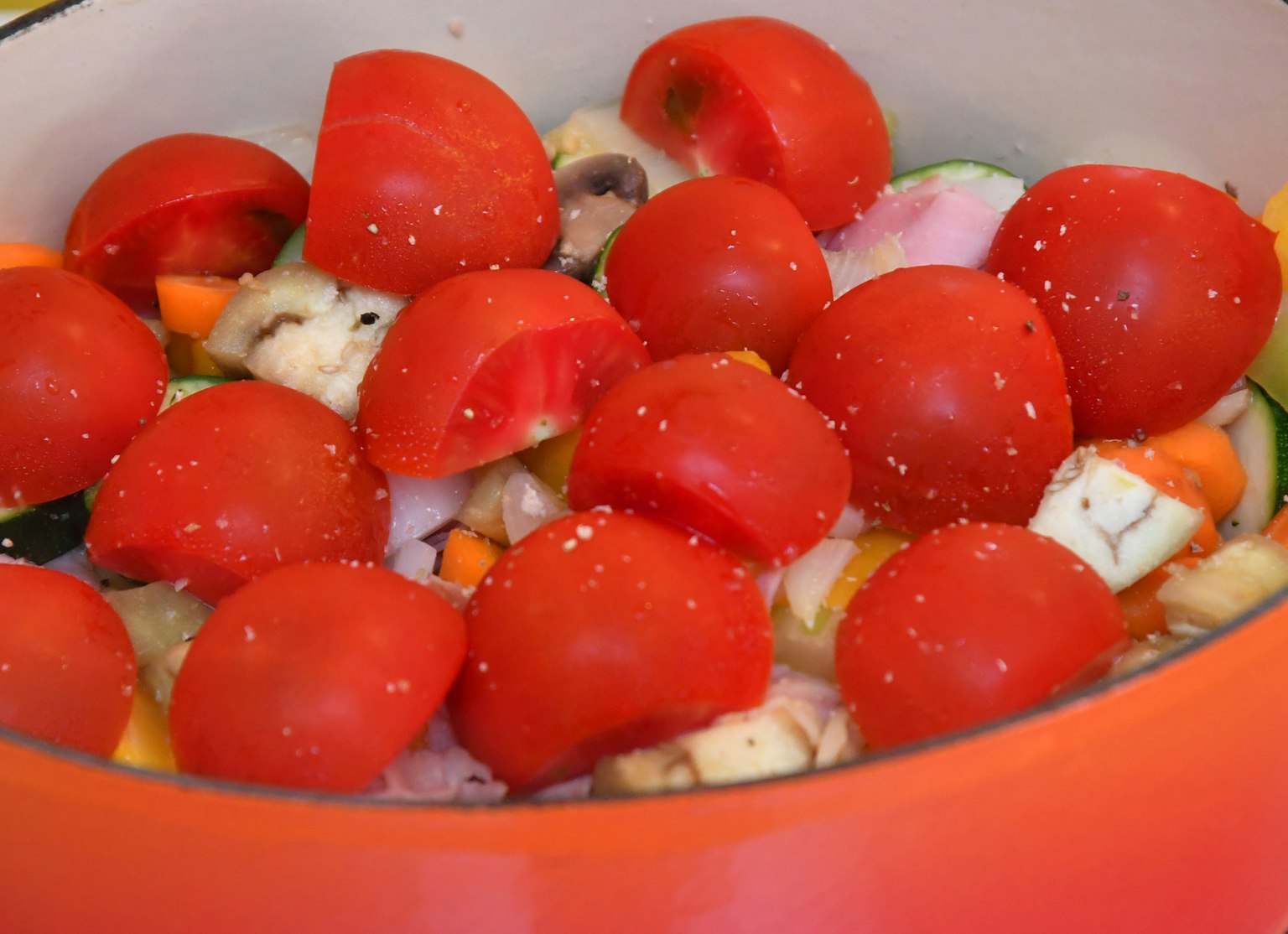 Une casserole remplie de tomates rouges vives et de légumes assortis