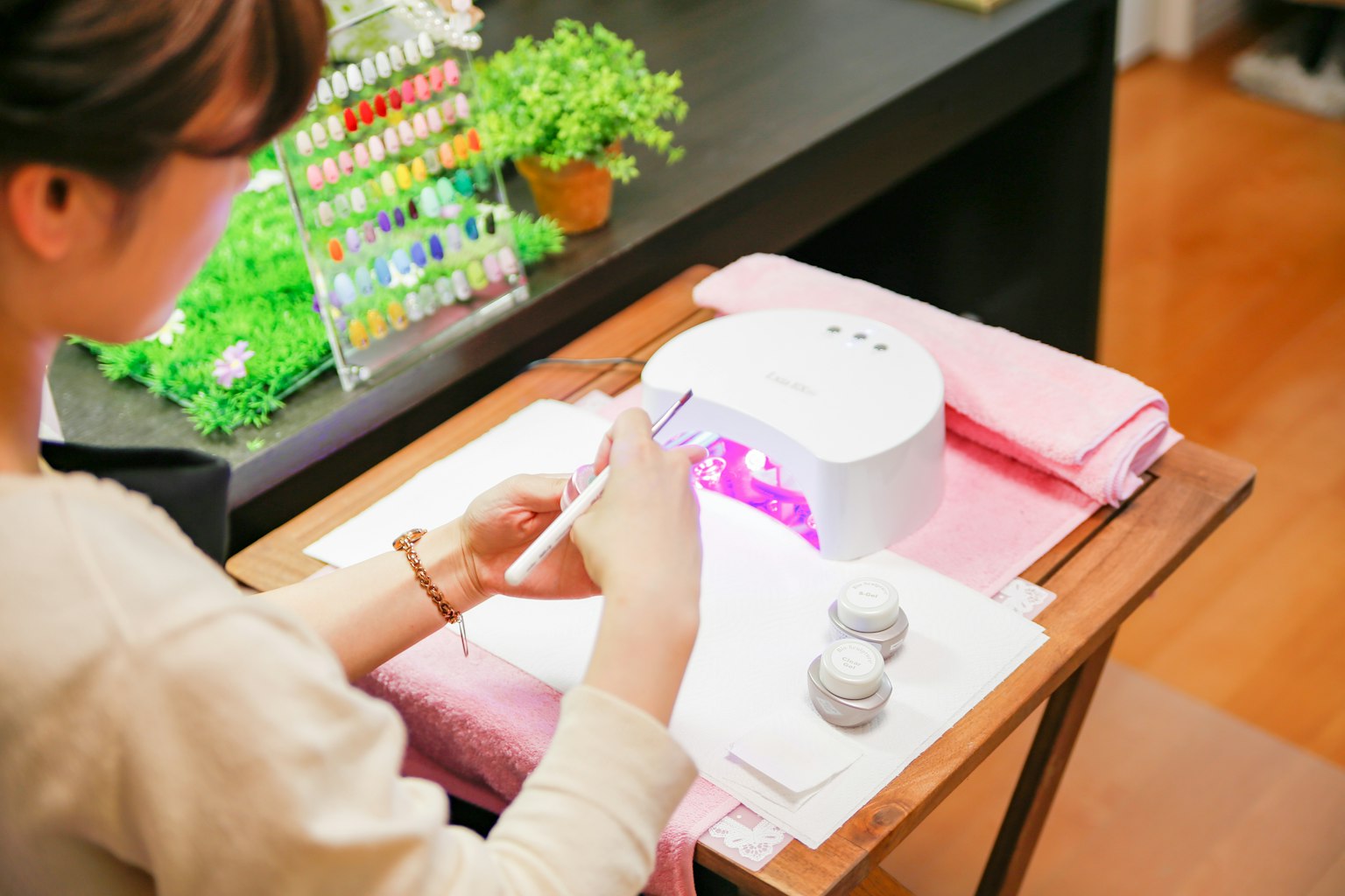 Eine Frau, die Nagelkunst genießt, arbeitet unter einer lila Nagellampe