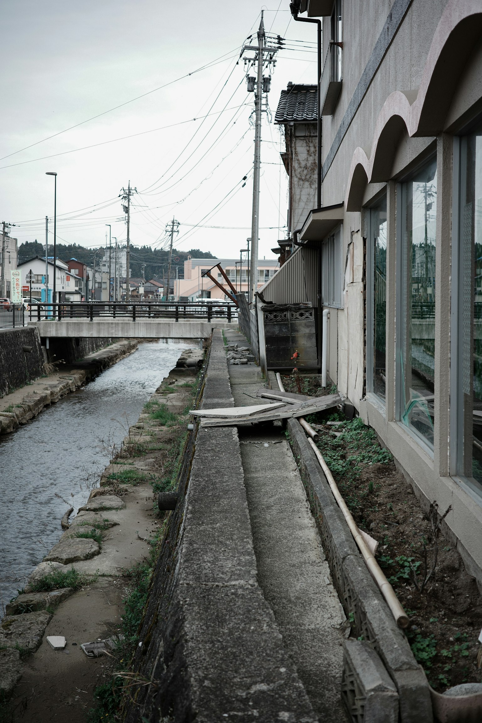 Blick auf einen Betonweg entlang eines Flusses mit einem alten Gebäude