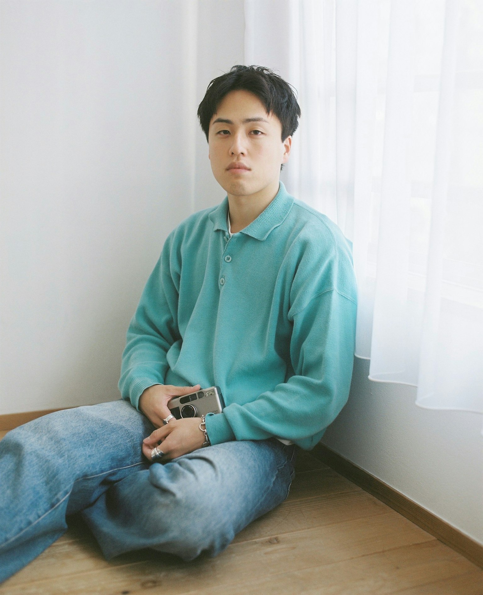 穿着蓝色毛衣的年轻男子坐在窗边