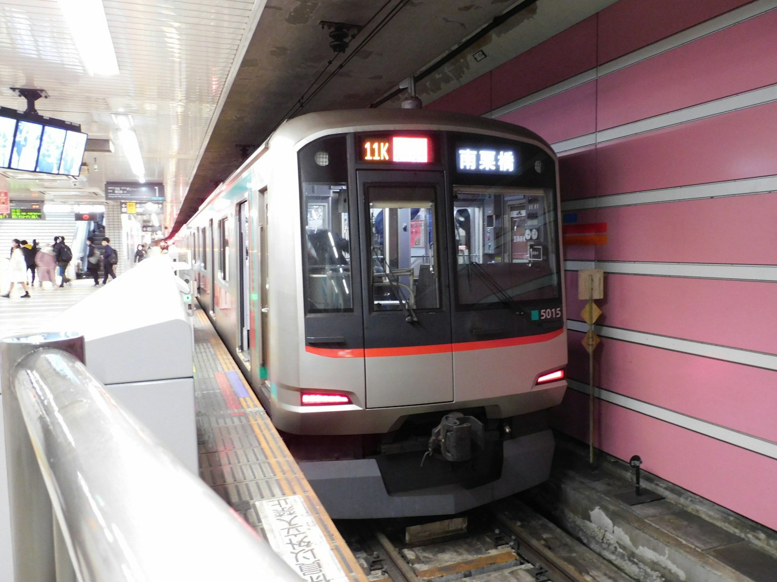 Train stopped at a station with distinctive pink walls