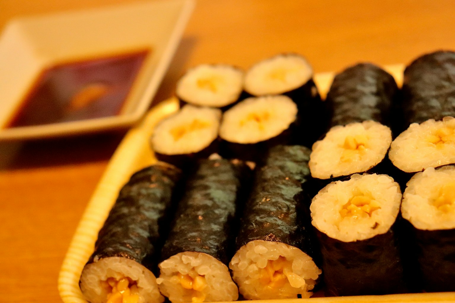Một đĩa sushi cuộn với nhiều loại nhân được trưng bày trên bàn gỗ