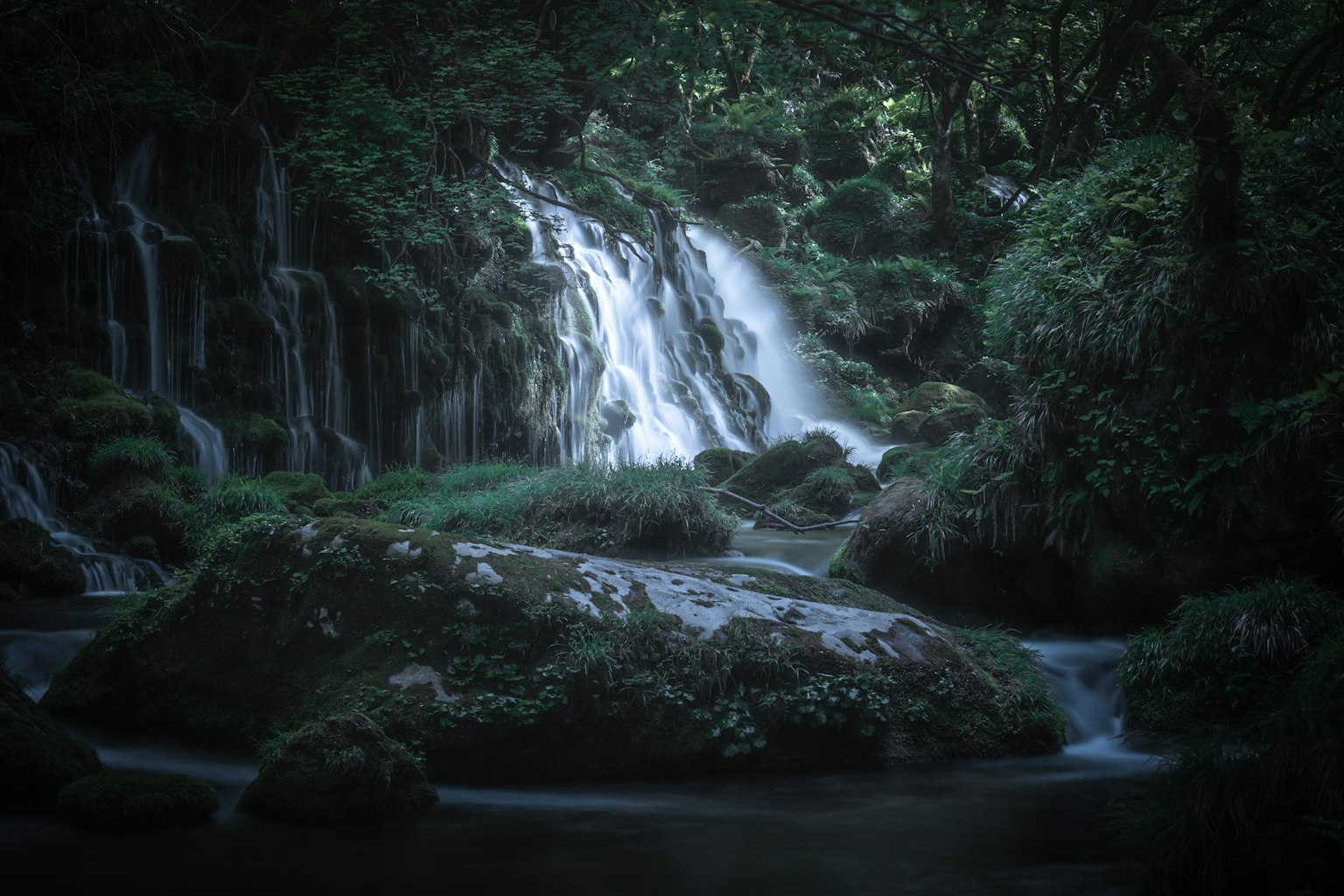 Una hermosa escena de una cascada rodeada de vegetación y agua tranquila